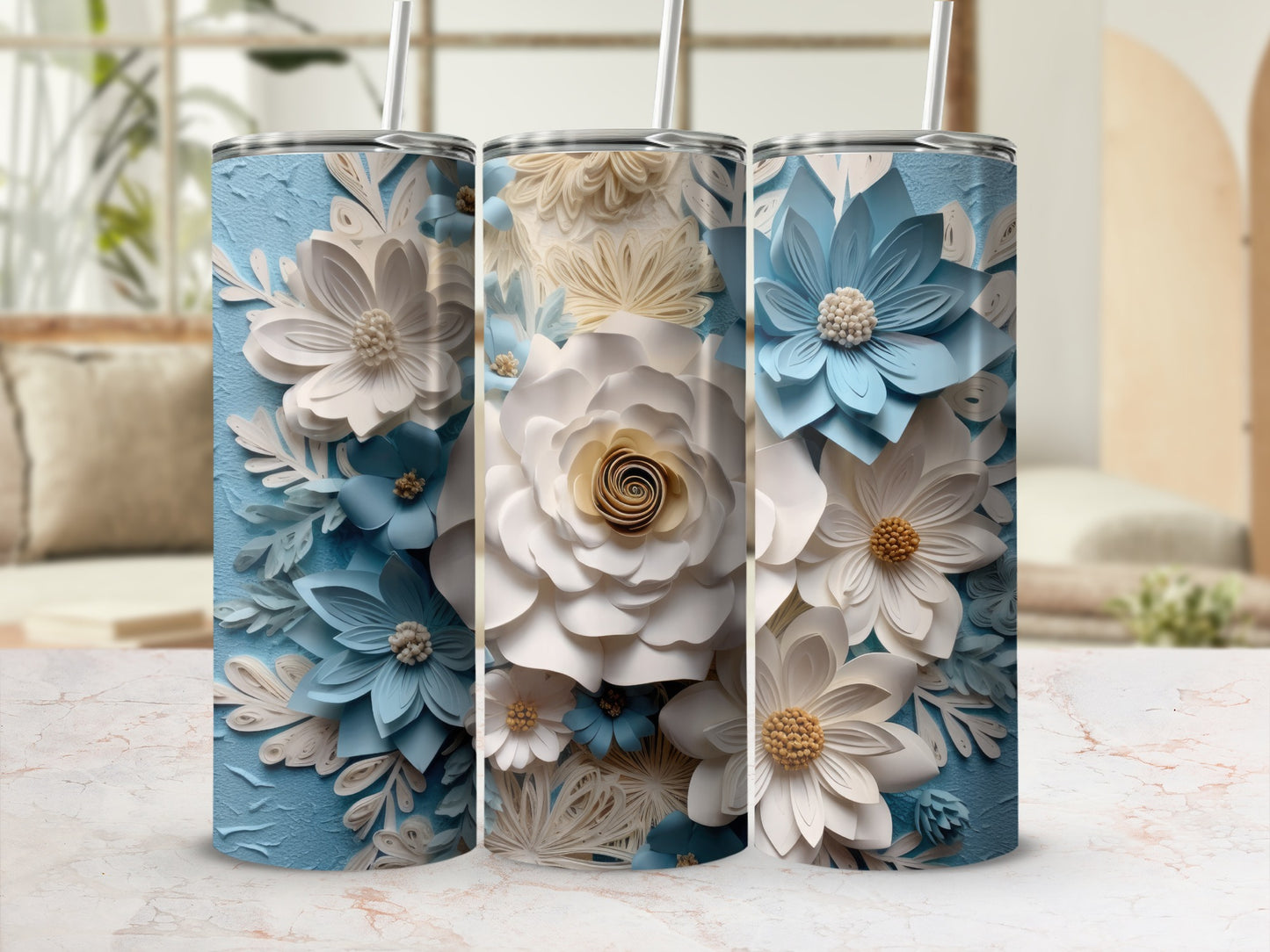 Three blue and white floral tumblers with straws on a marble surface.