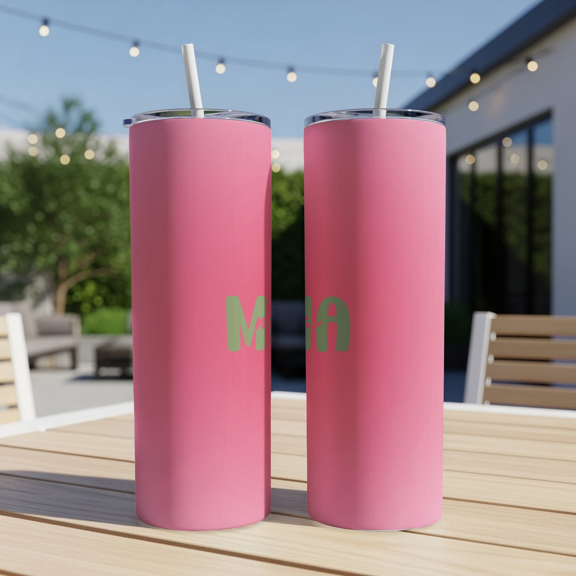 Two pink tumblers with green "Mama" text stand on a wooden table.