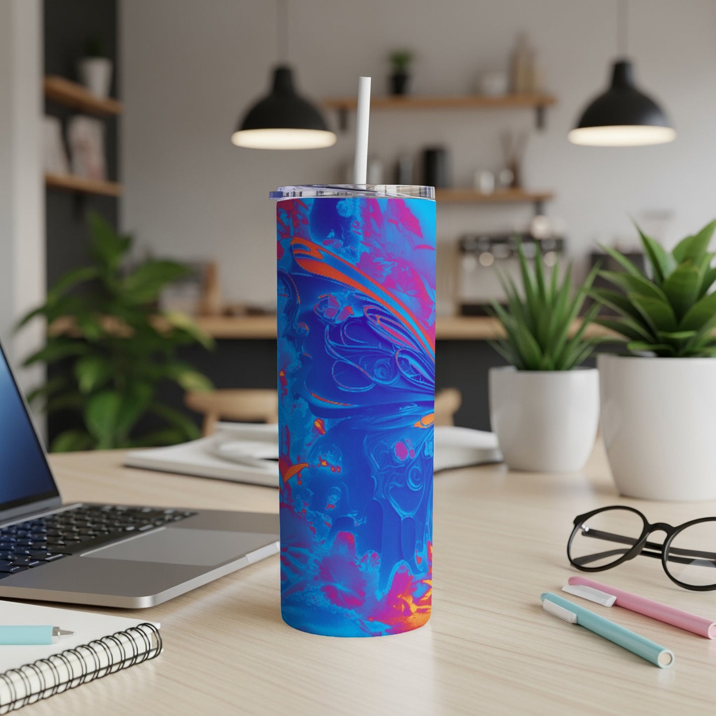 Blue and pink abstract patterned tumbler with straw on desk.