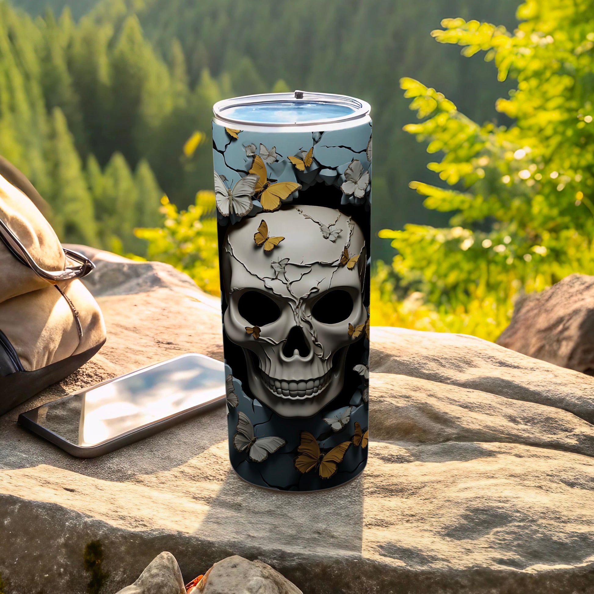 Skull and butterflies design on a travel tumbler with a smartphone and backpack outdoors.