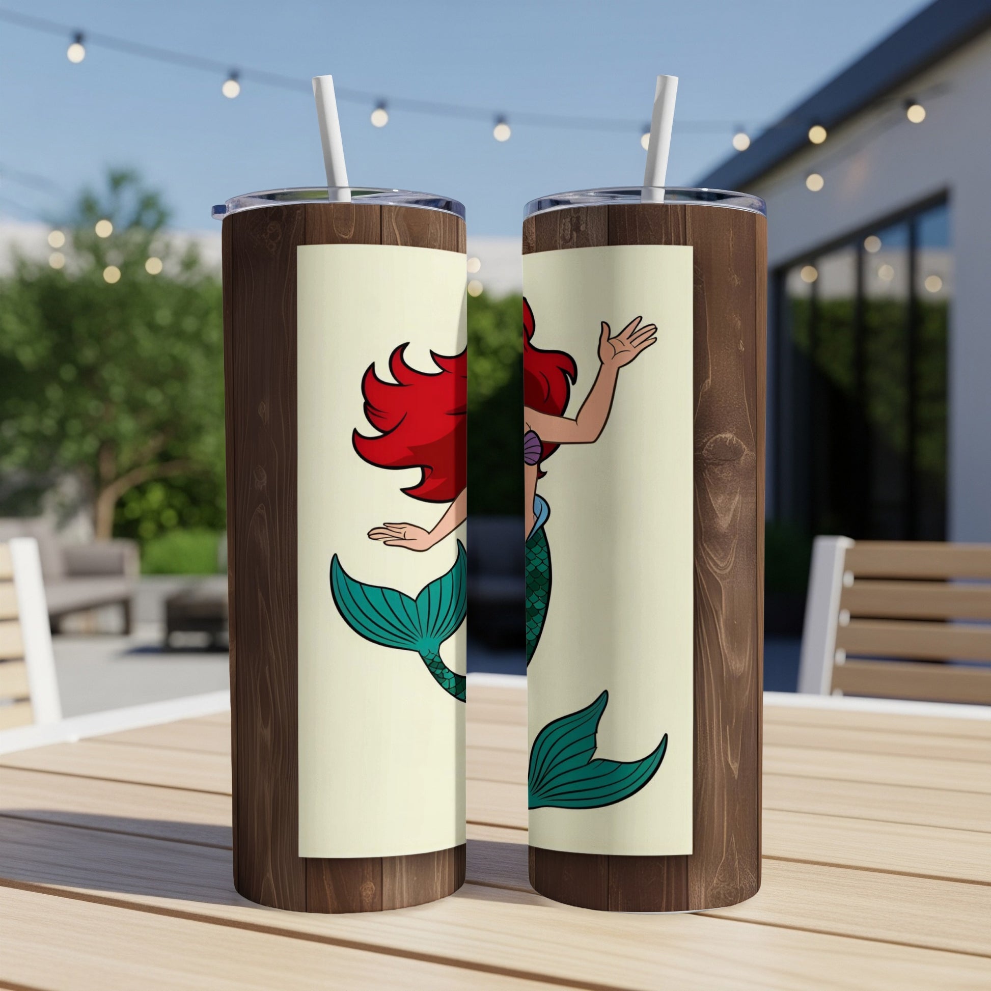 Two tumblers featuring Ariel the mermaid on a wooden table.