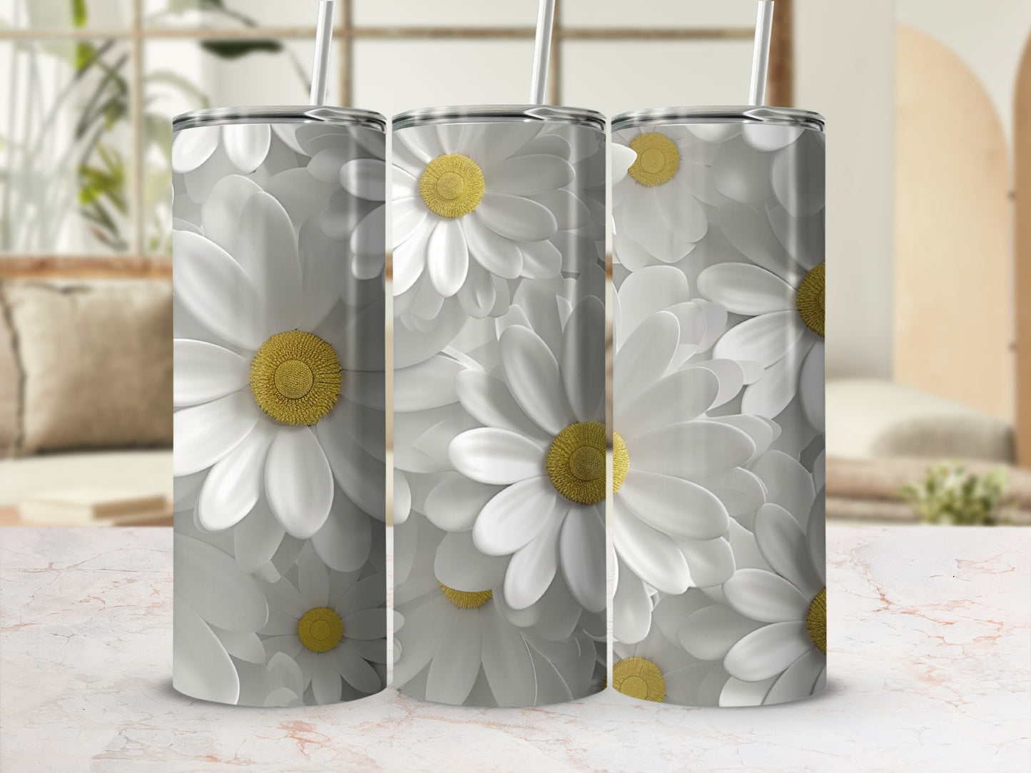 Three white daisy print tumblers with straws on a marble surface.