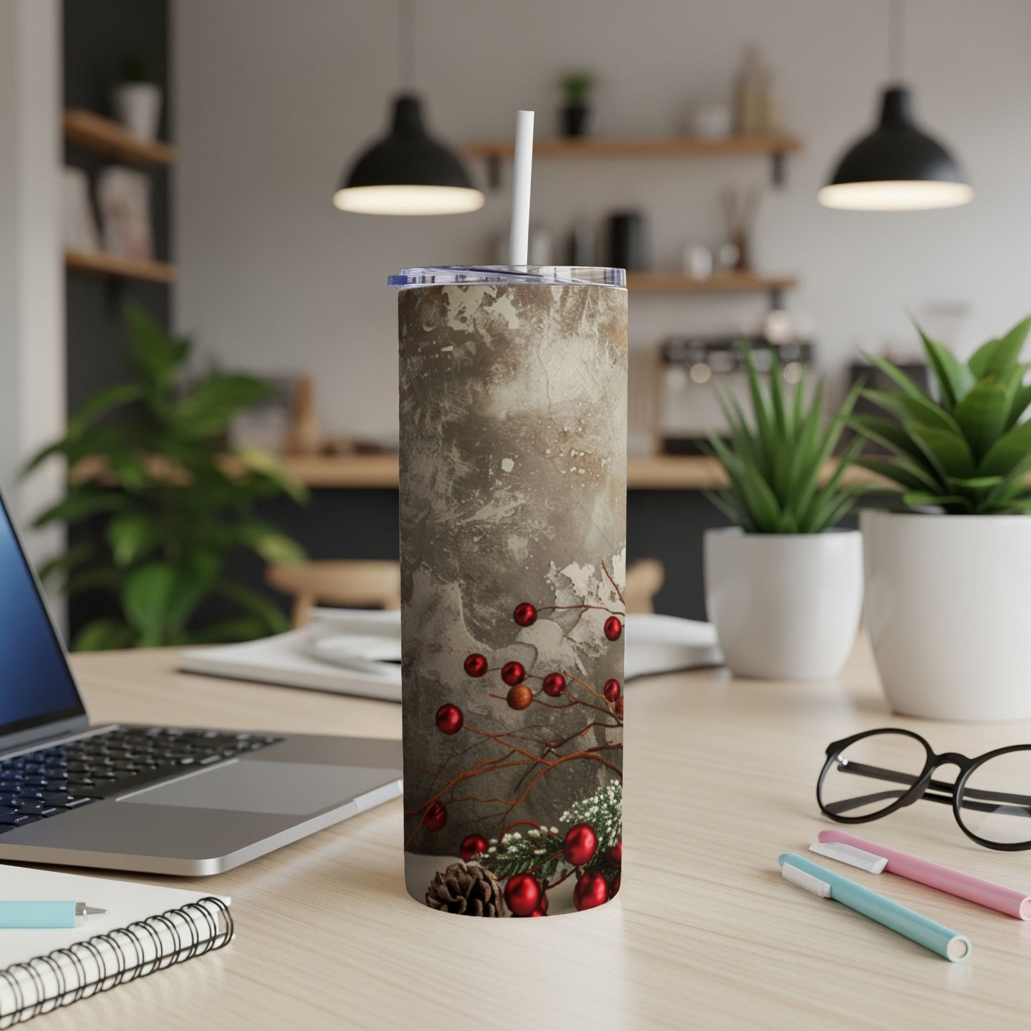 Marble-patterned tumbler with red berries and pine sprigs on a desk.