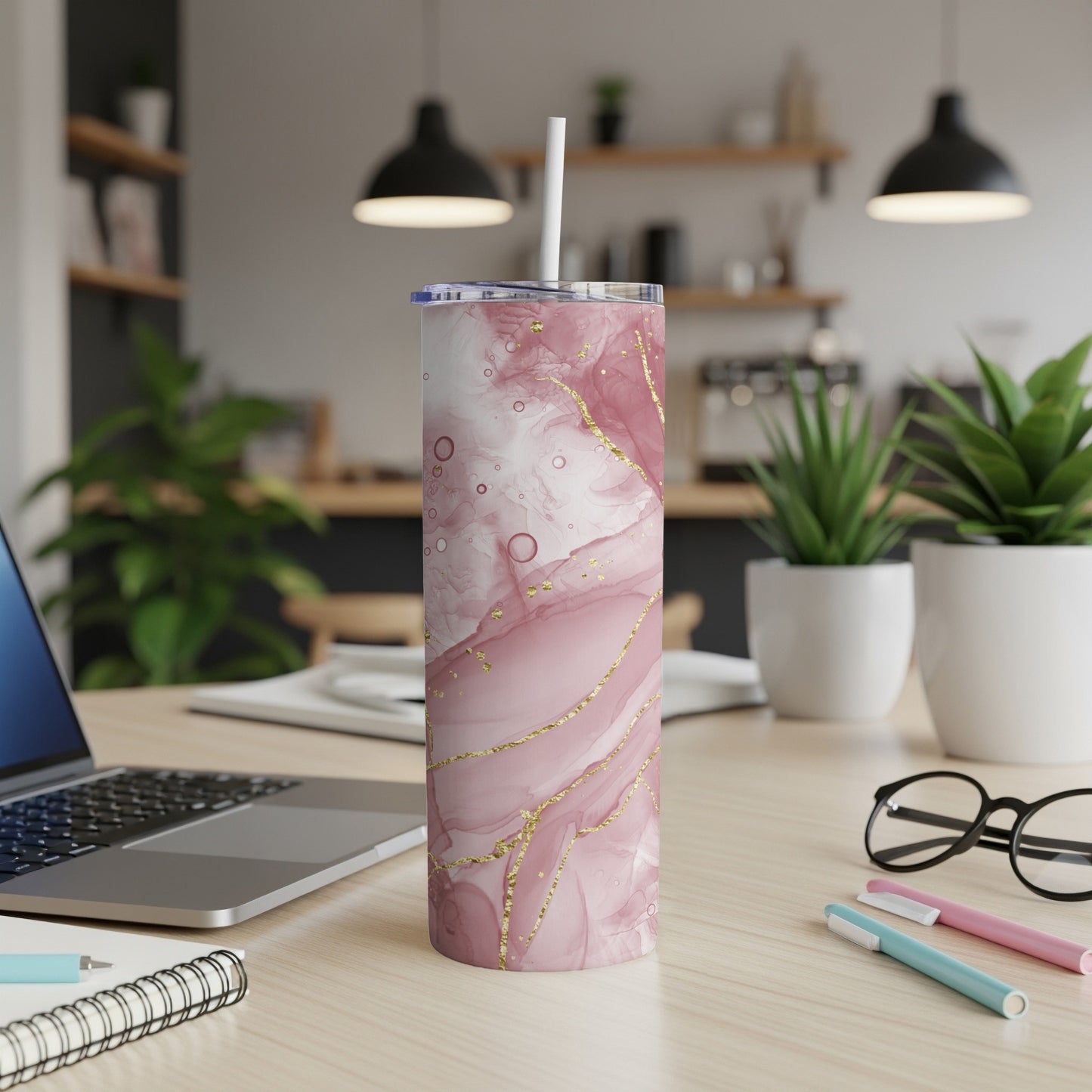 Pink marble tumbler with gold veins and straw on a desk.
