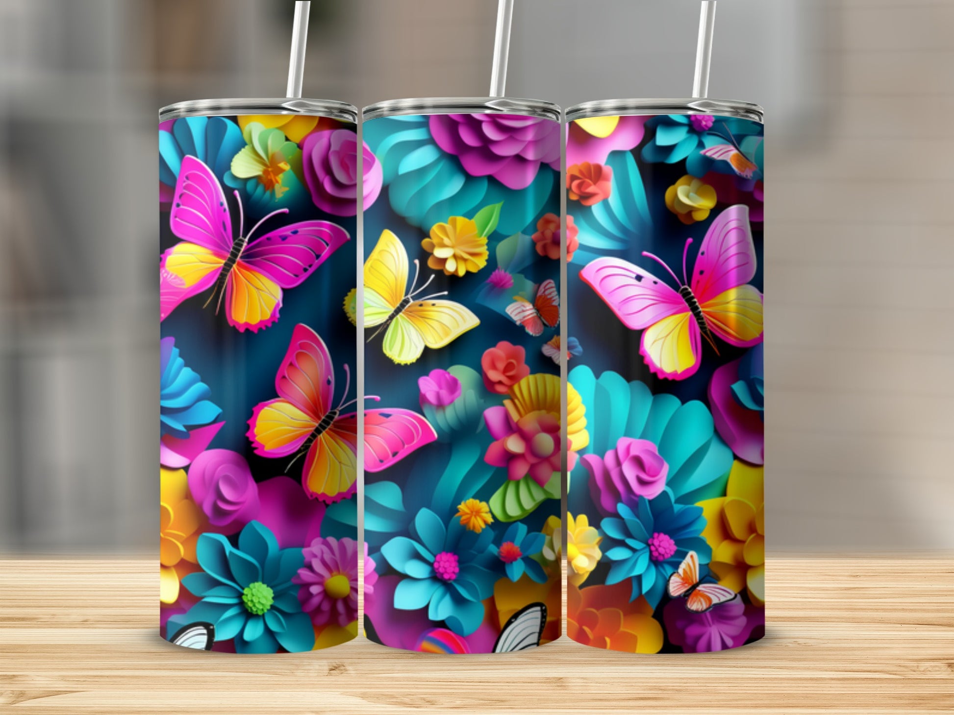Three tumblers with colorful floral and butterfly designs on a wooden surface.