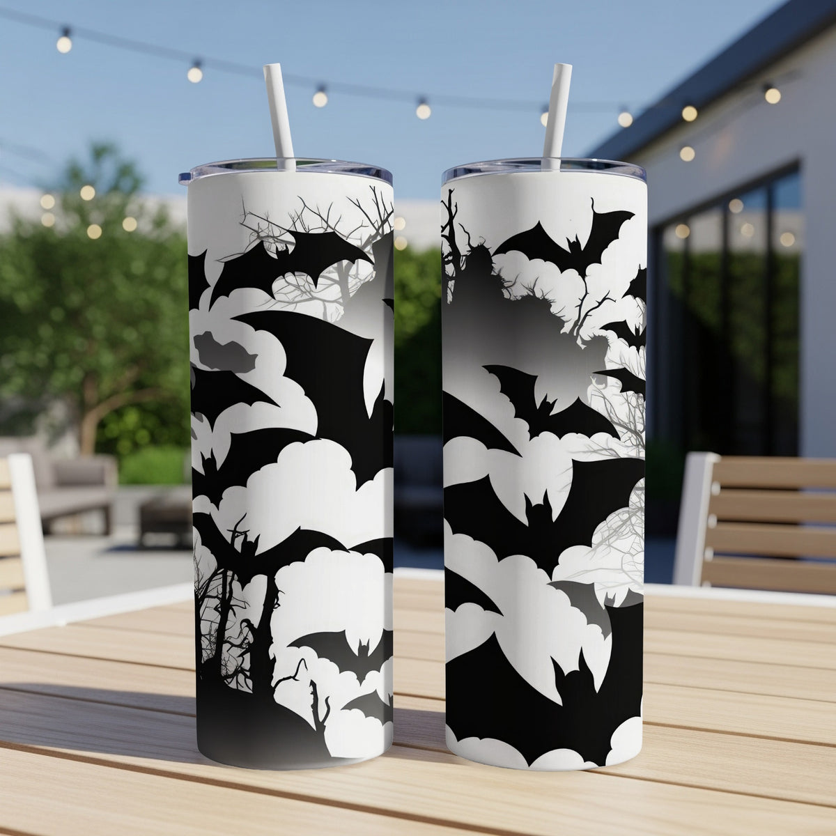 Two tumblers with black bat and cloud patterns on a wooden table.