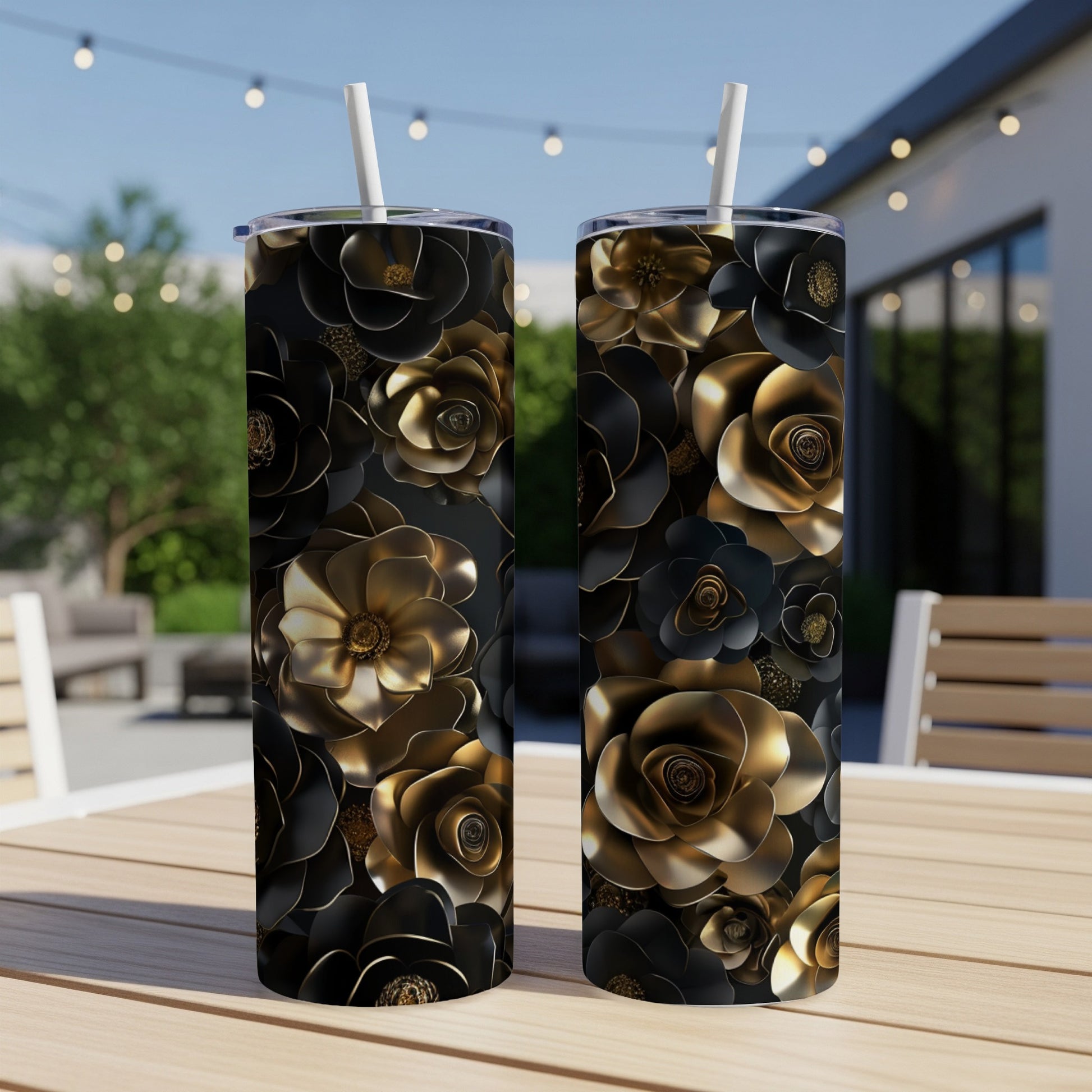 Two black tumblers with gold floral pattern on a wooden table.