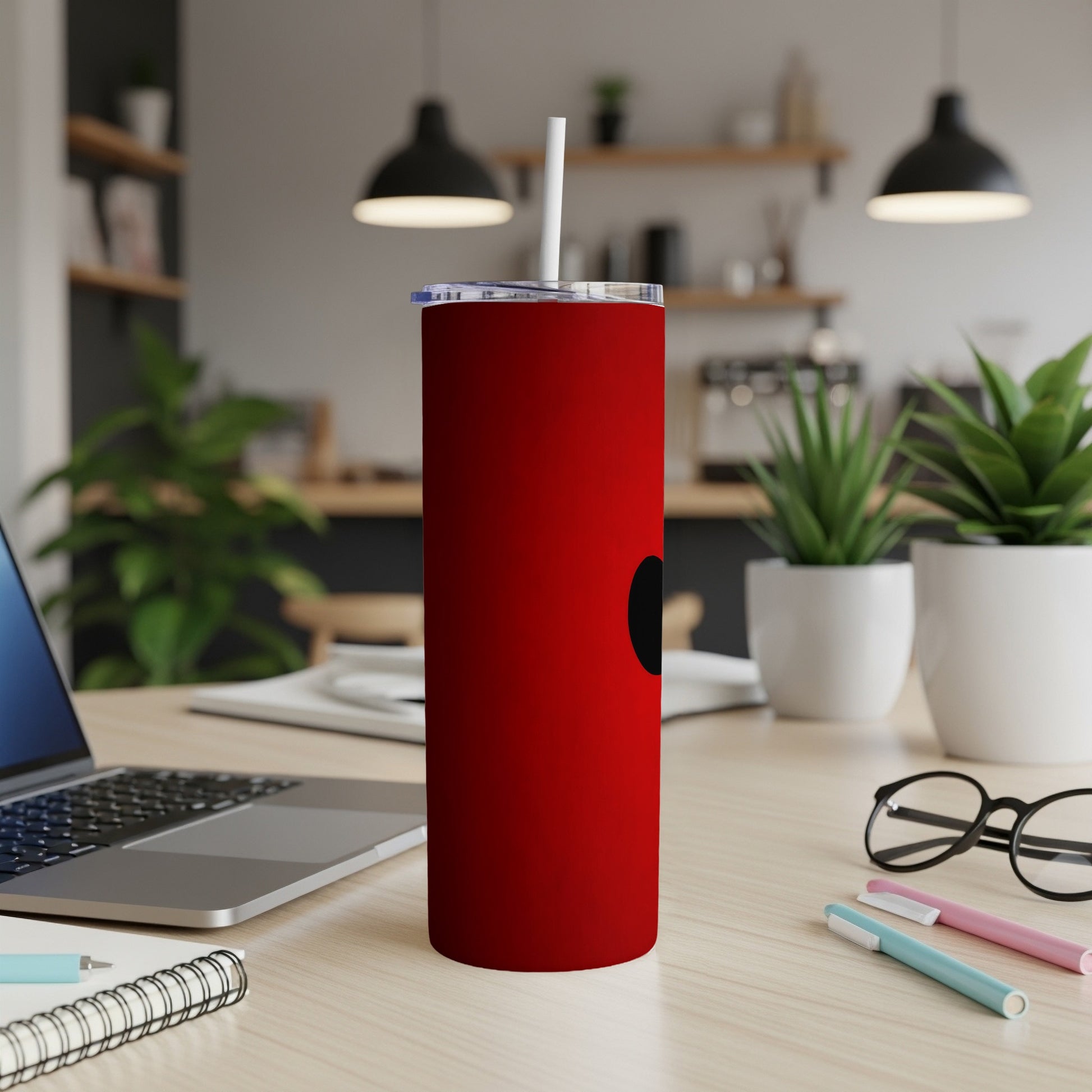 Red tumbler with white straw and black circle design on a desk.