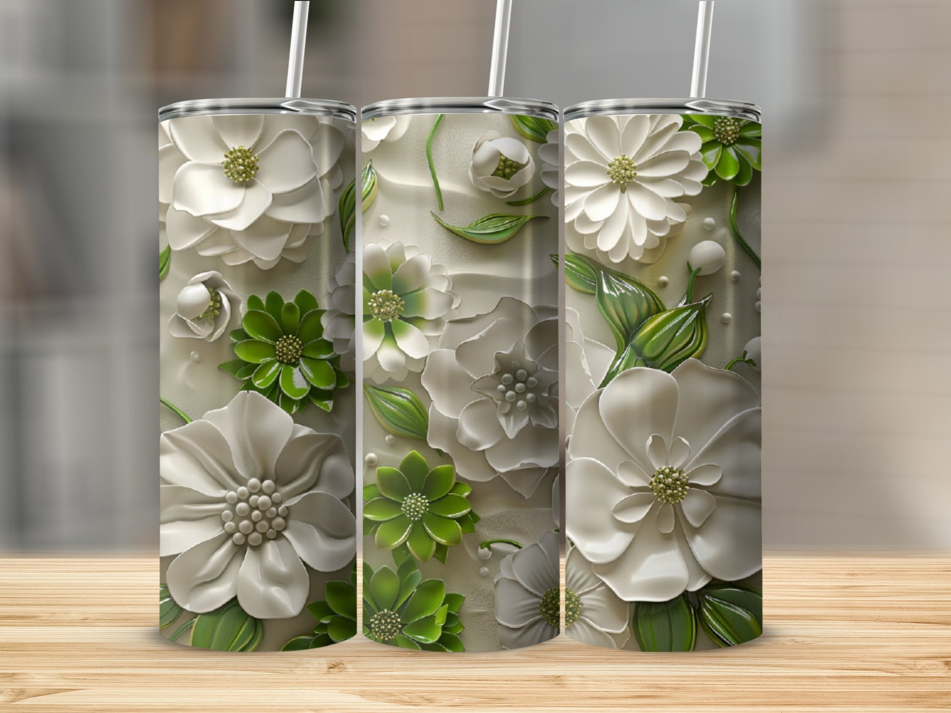 Three white and green floral embossed tumblers on a wooden surface.