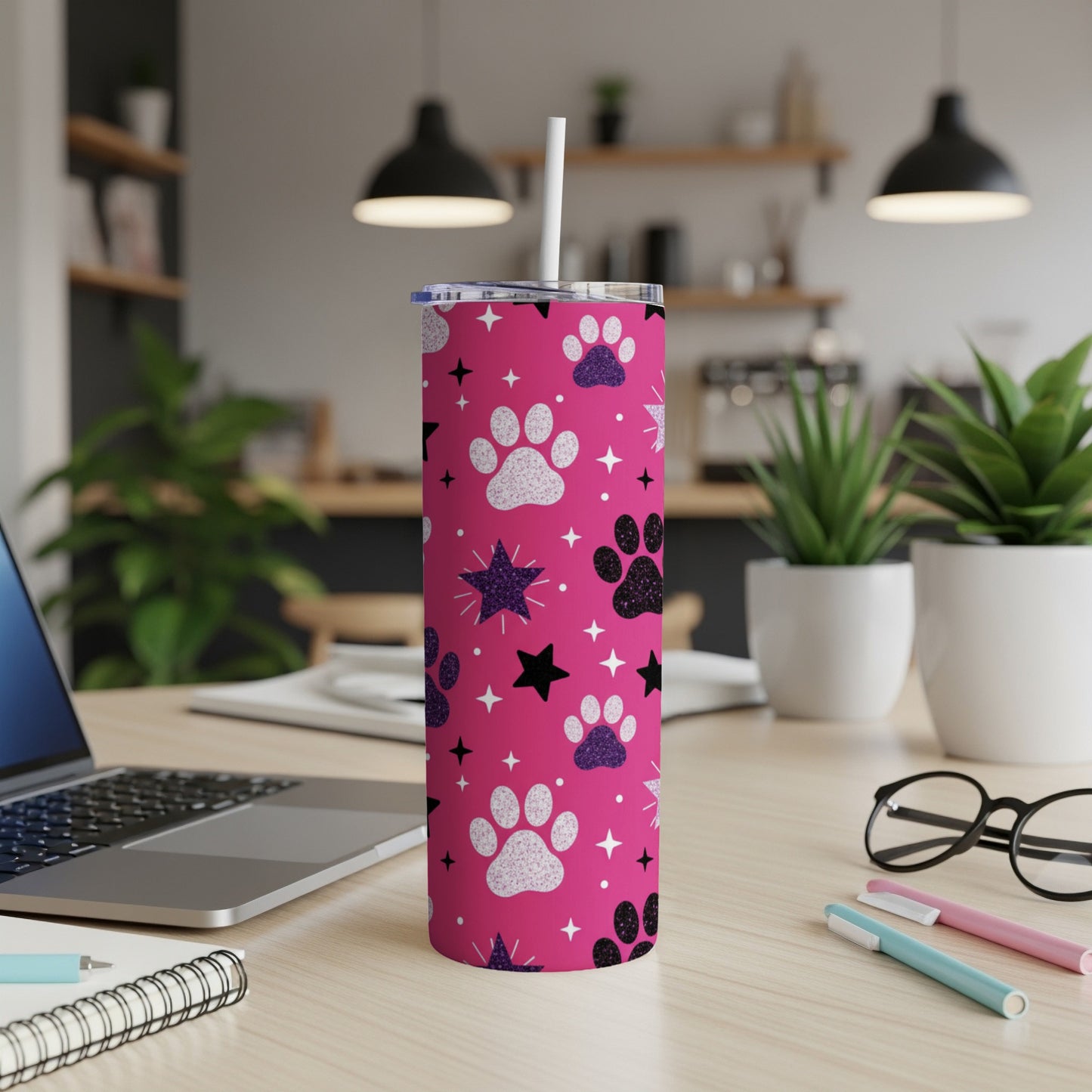 Pink tumbler with paw prints and stars, a white straw inserted.