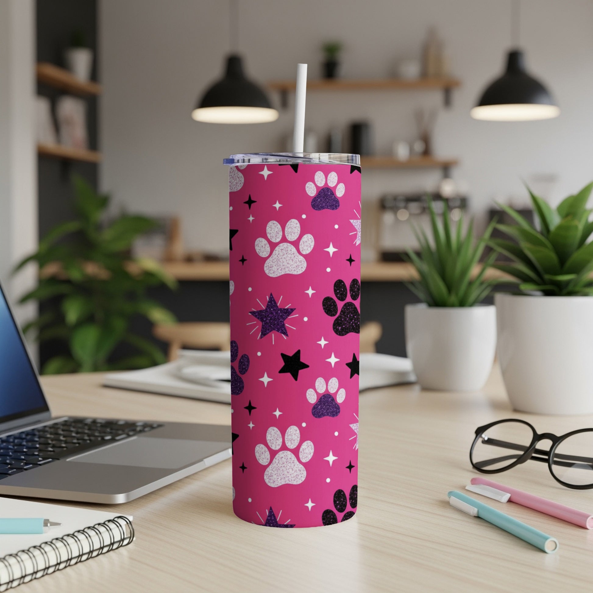 Pink tumbler with paw prints and stars, a white straw inserted.