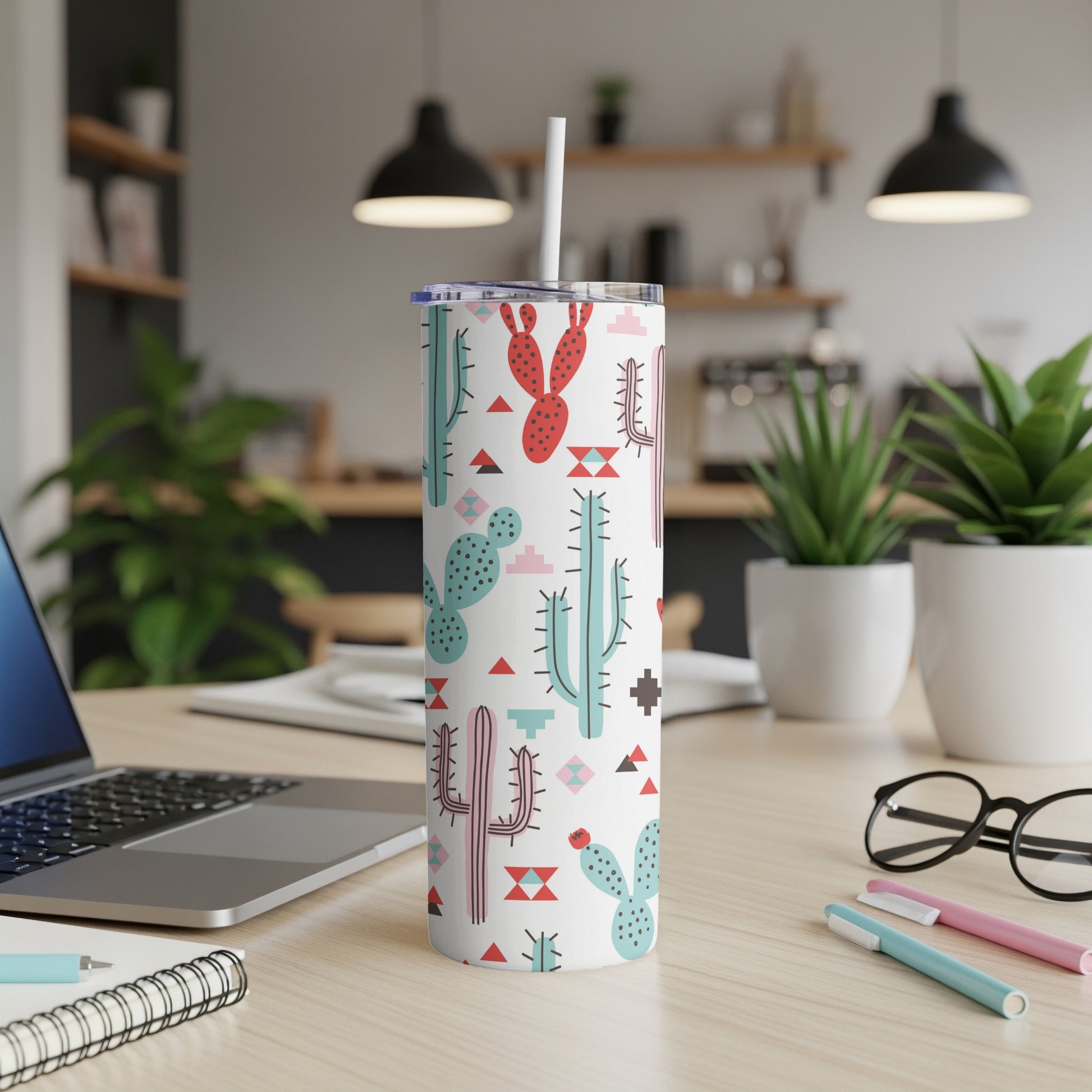 White tumbler with a pattern of colorful cartoon cacti and geometric shapes, straw inserted.