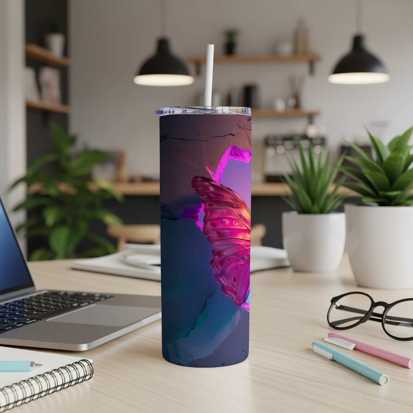 Pink butterfly design on a stainless steel tumbler with straw on a desk.