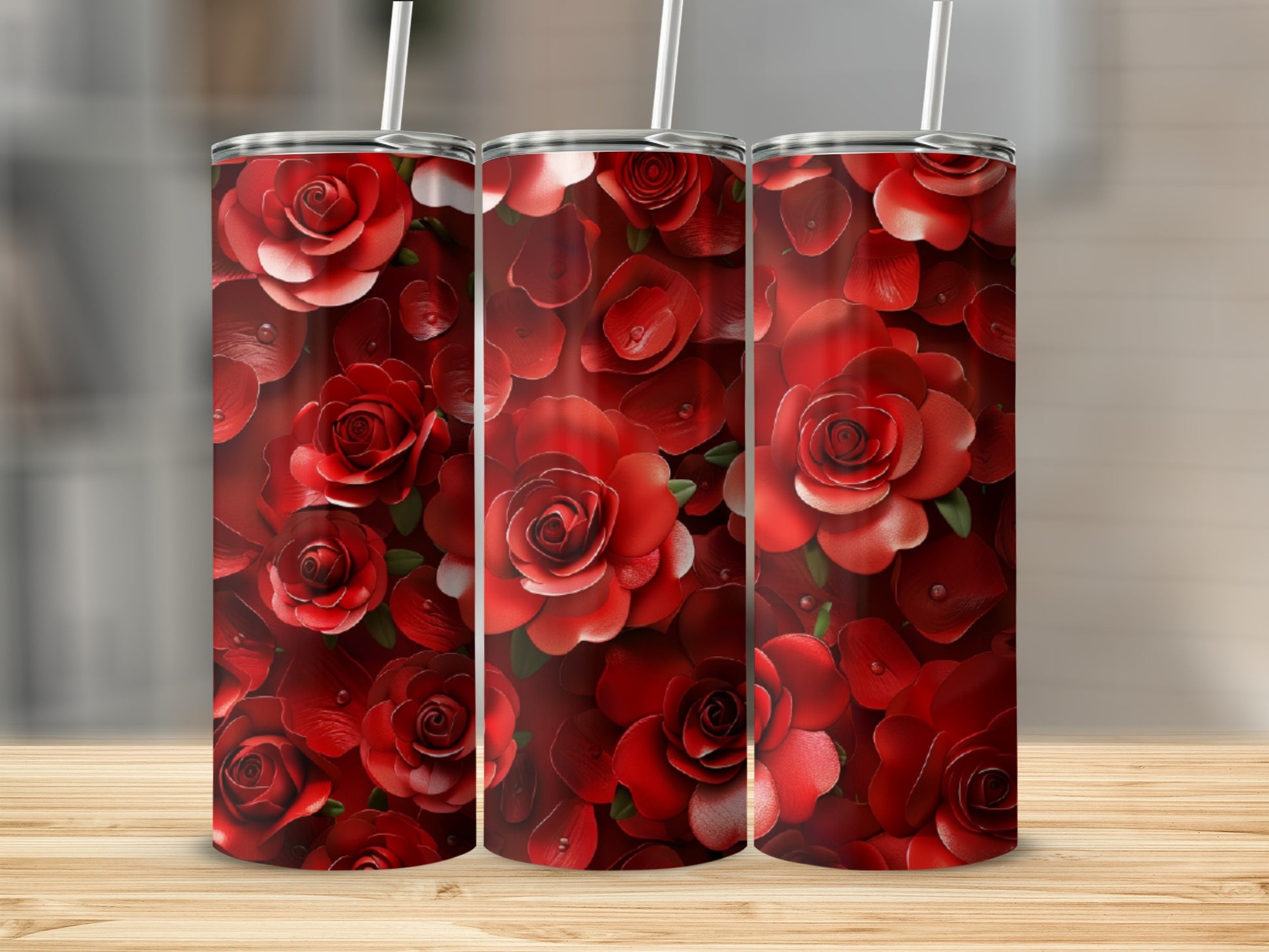 Three red rose pattern tumblers with straws on a wooden surface.