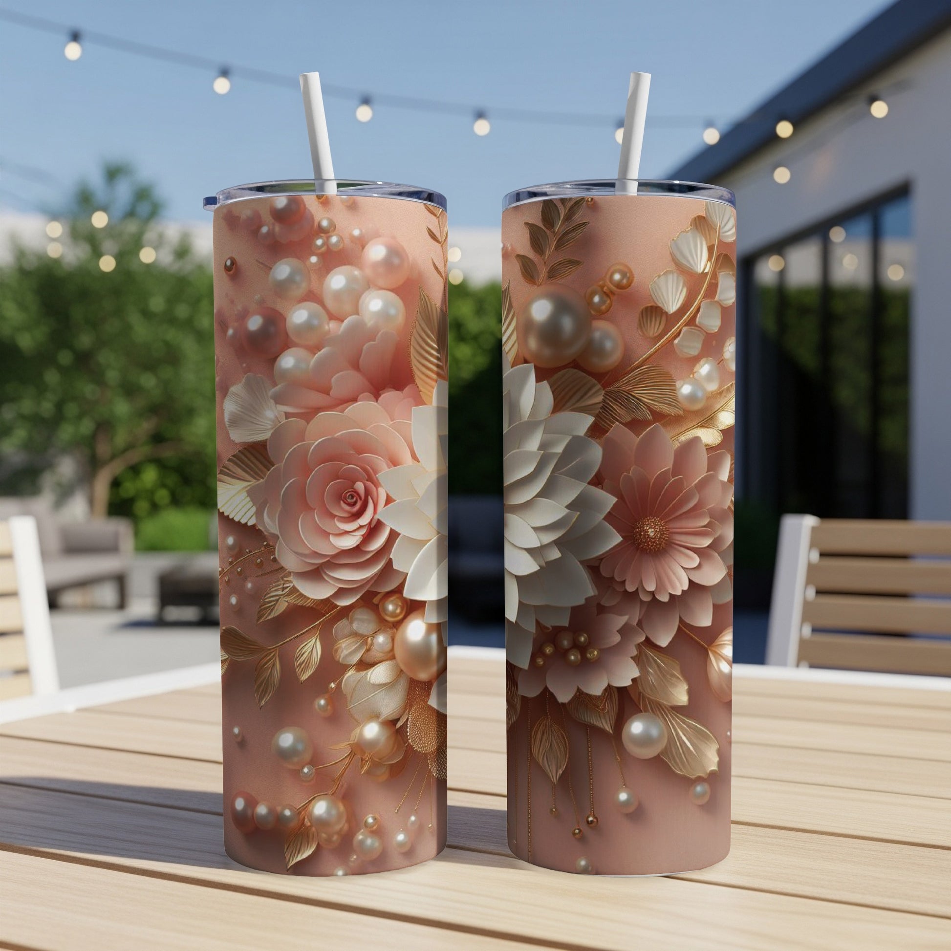 Two pink tumblers with floral and pearl designs sit on a wooden table.