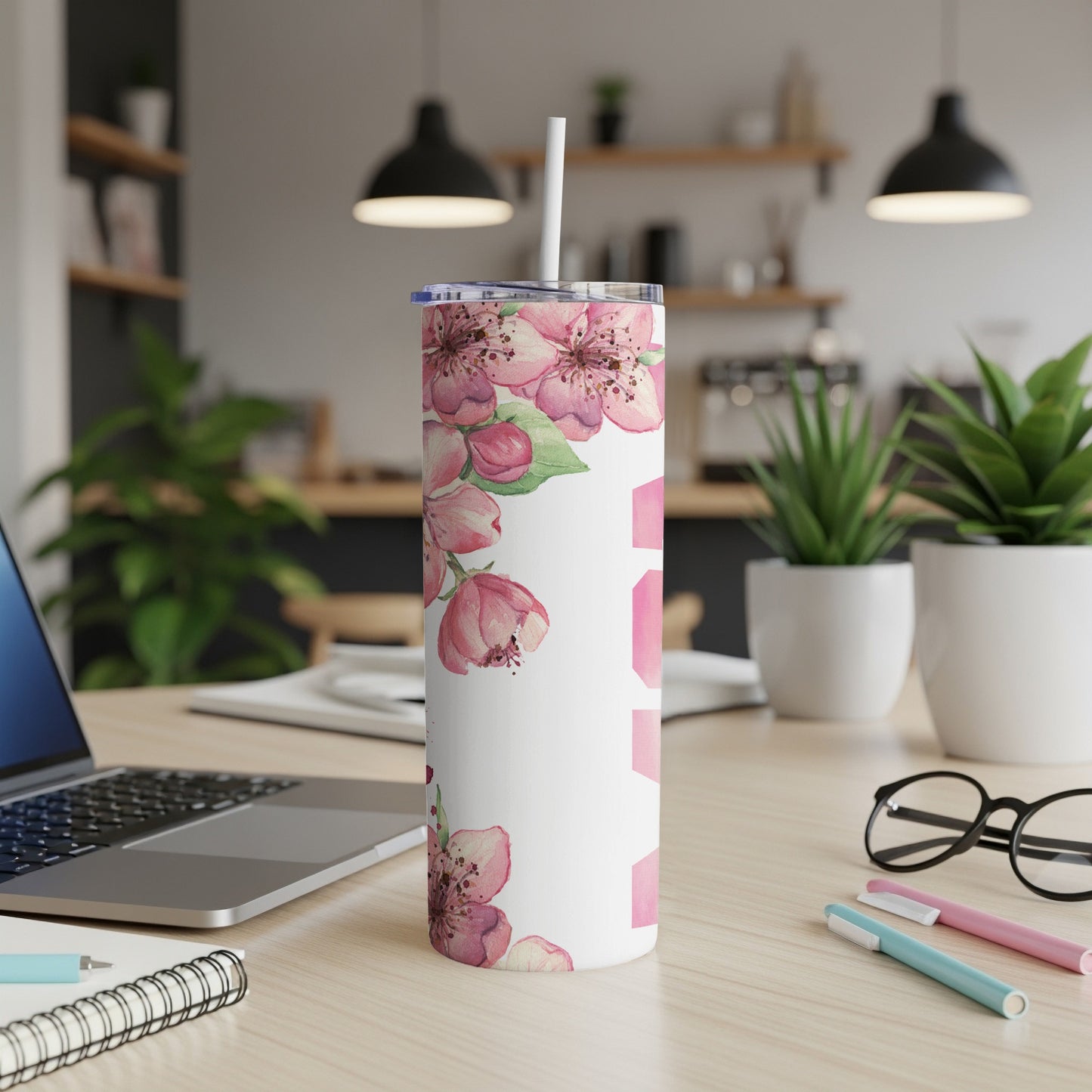 White tumbler with pink cherry blossoms and blurred kitchen background.