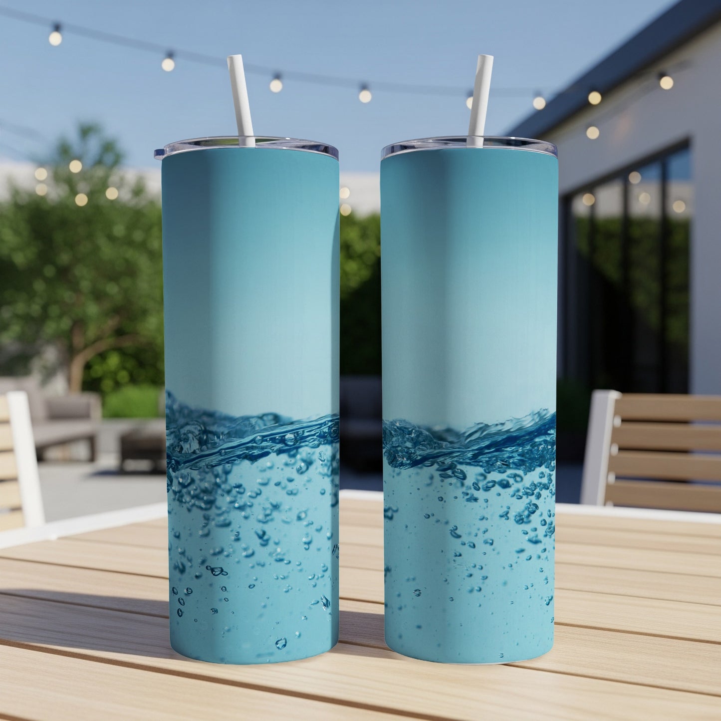 Two tall, blue tumblers with bubbly water design and straws on a table.