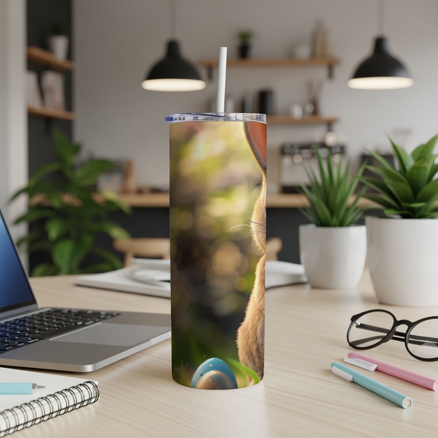 Brown bunny on a tumbler with a straw, on a desk.