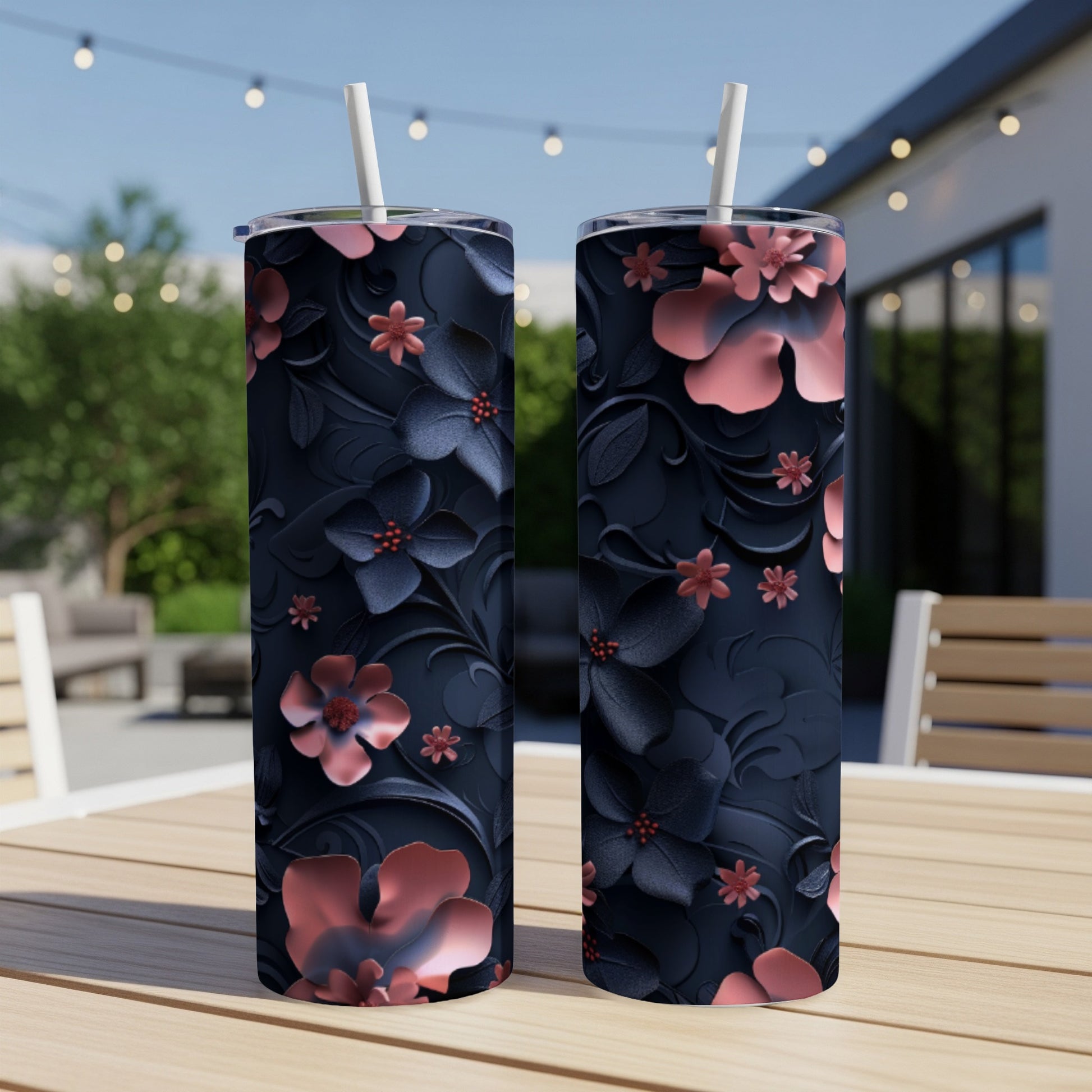 Two dark blue tumblers with embossed pink floral patterns and straws.