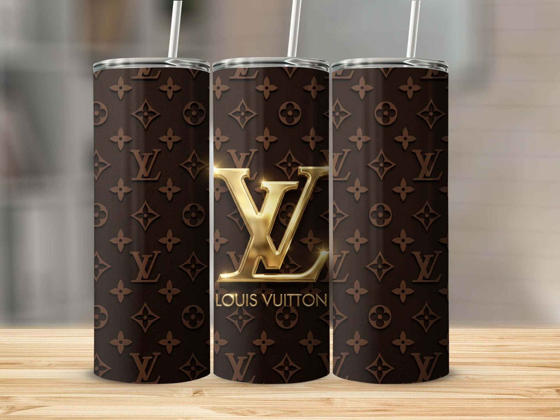 Three Louis Vuitton pattern tumblers with gold logos and straws.