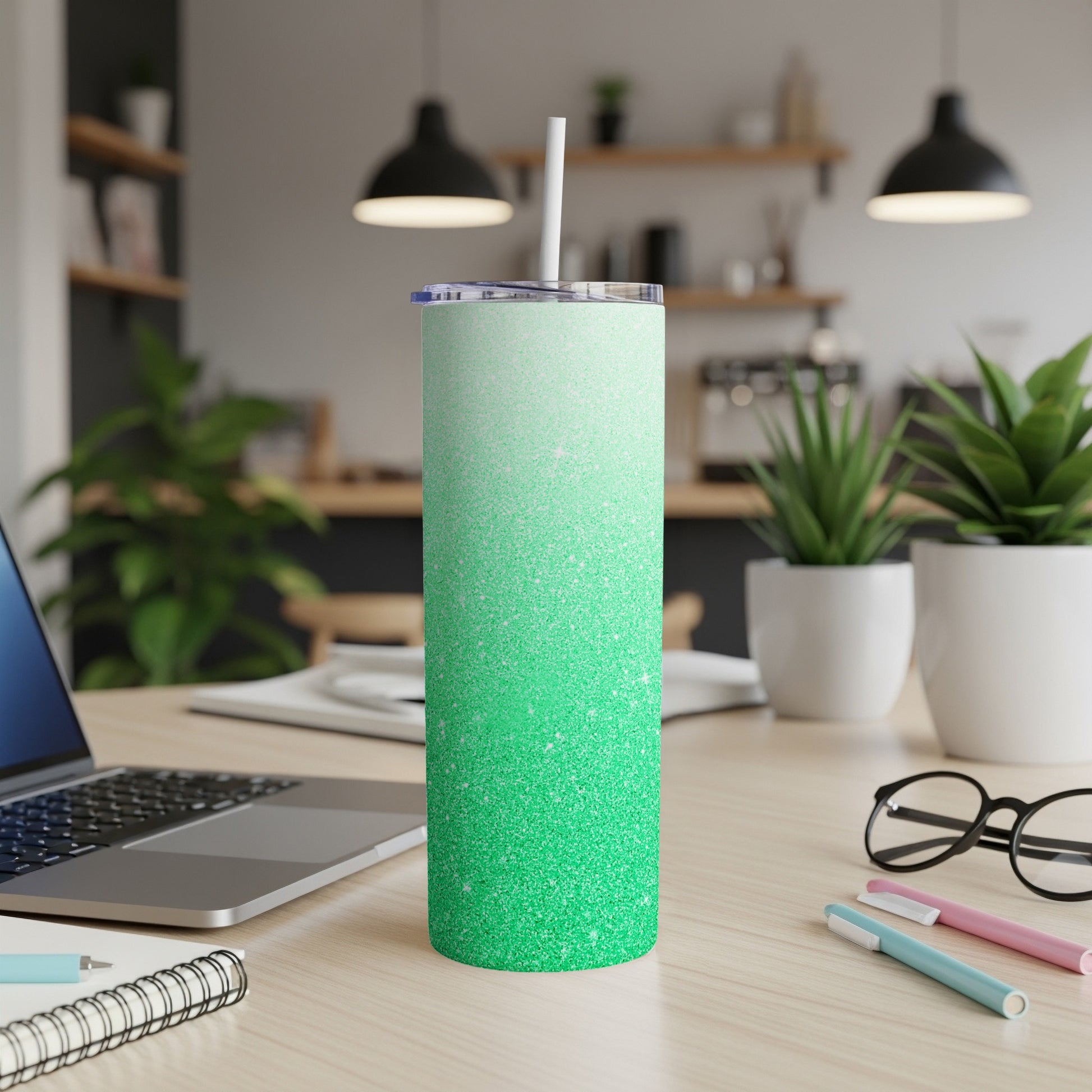 Green glitter ombre tumbler with straw on a desk.