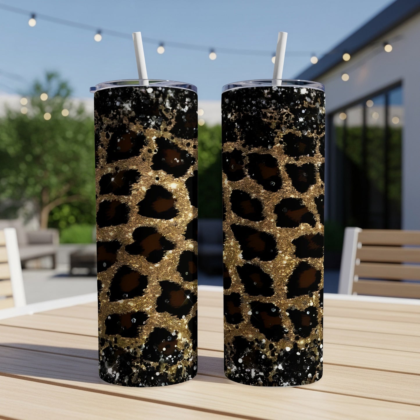Two tall tumblers with leopard print and gold glitter on an outdoor table.