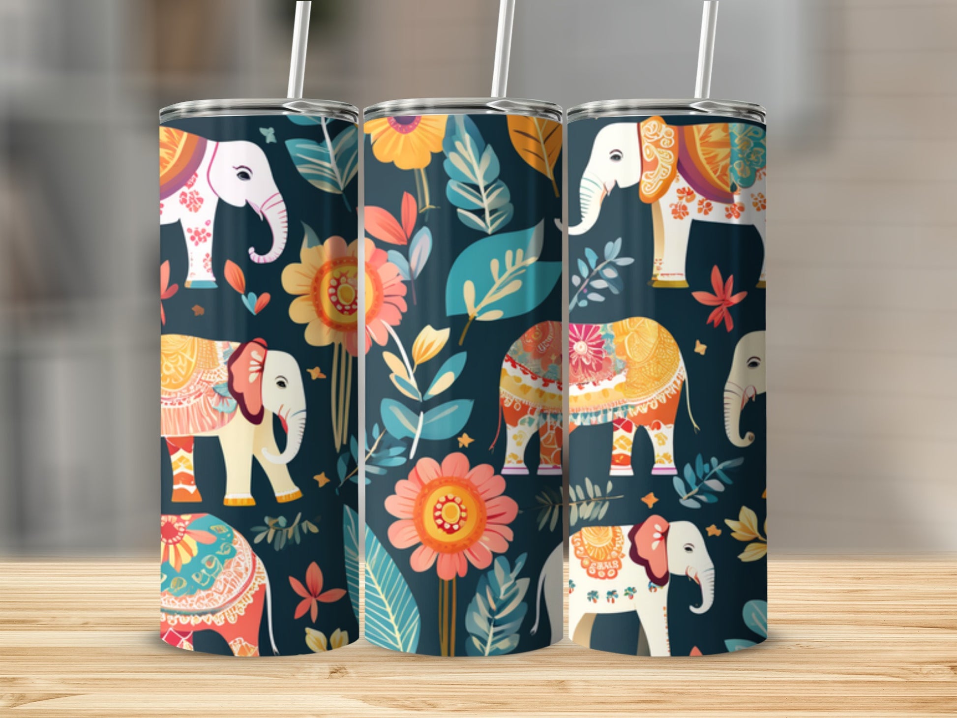 Three tumblers with colorful elephant and floral patterns on a wooden surface.