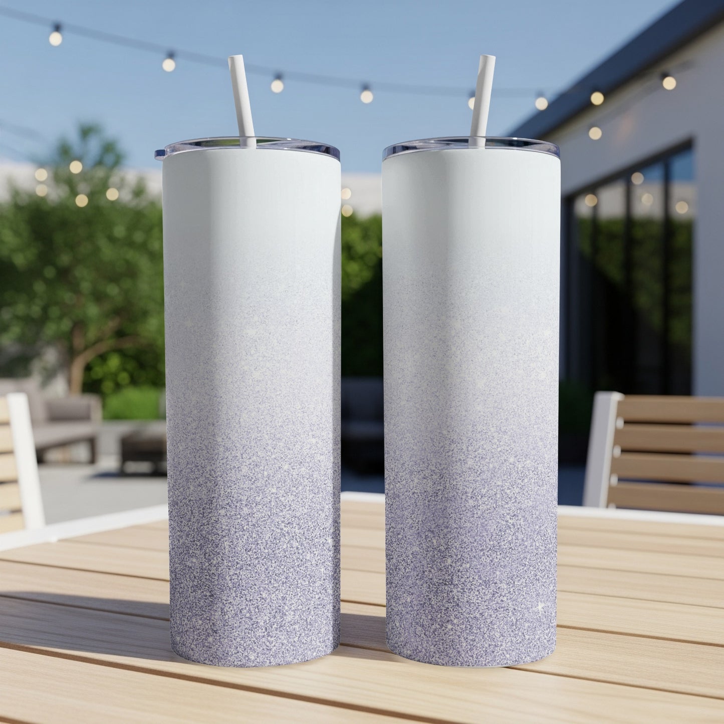 Two white and purple glitter ombre tumblers with straws on a wooden table.