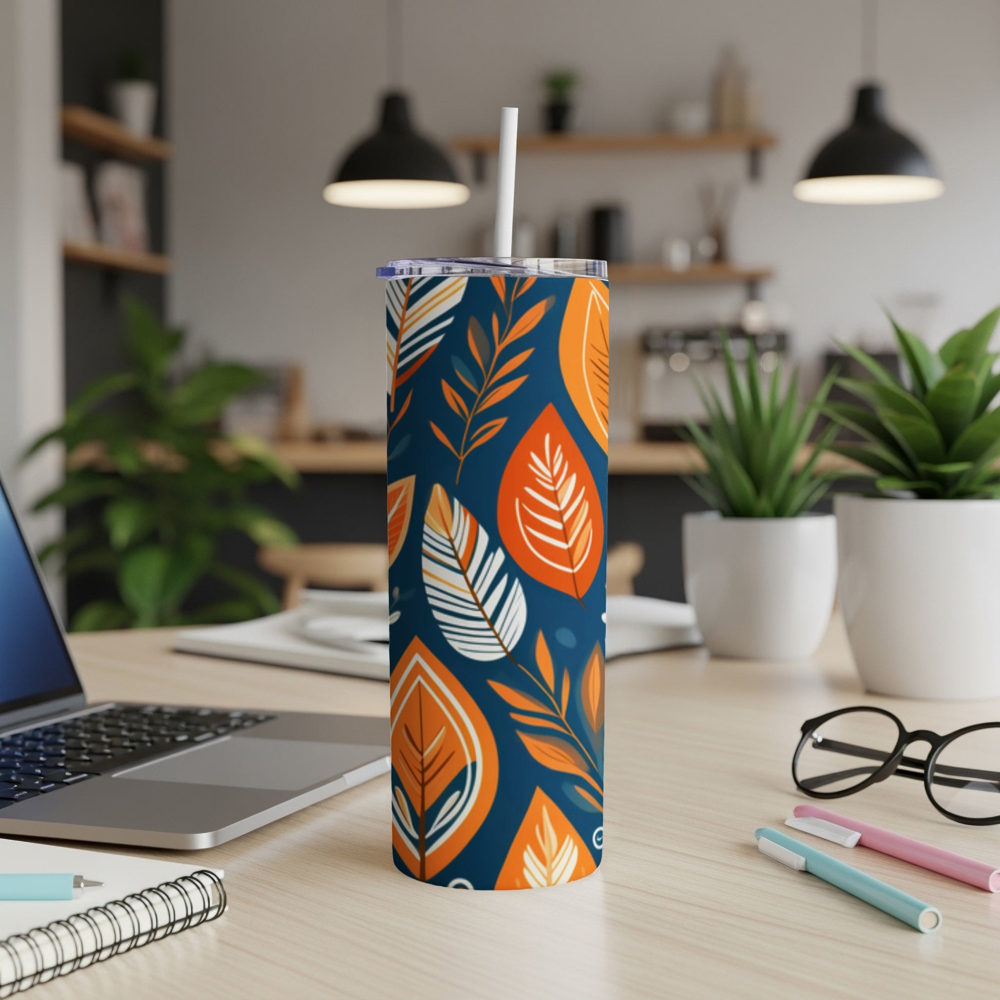 Navy blue tumbler with white straw, featuring a pattern of orange and white leaves.