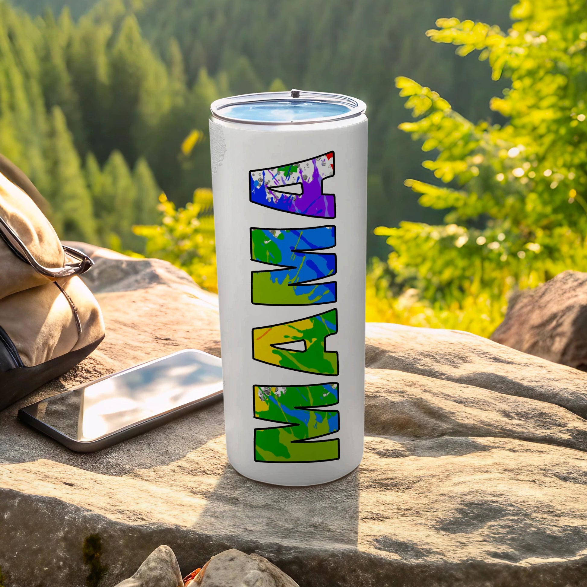 White tumbler with colorful "MAMA" text, outdoors with backpack and phone.