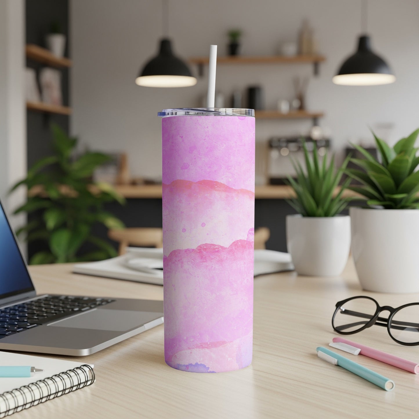 Pink and purple watercolor tumbler with white straw on a desk.