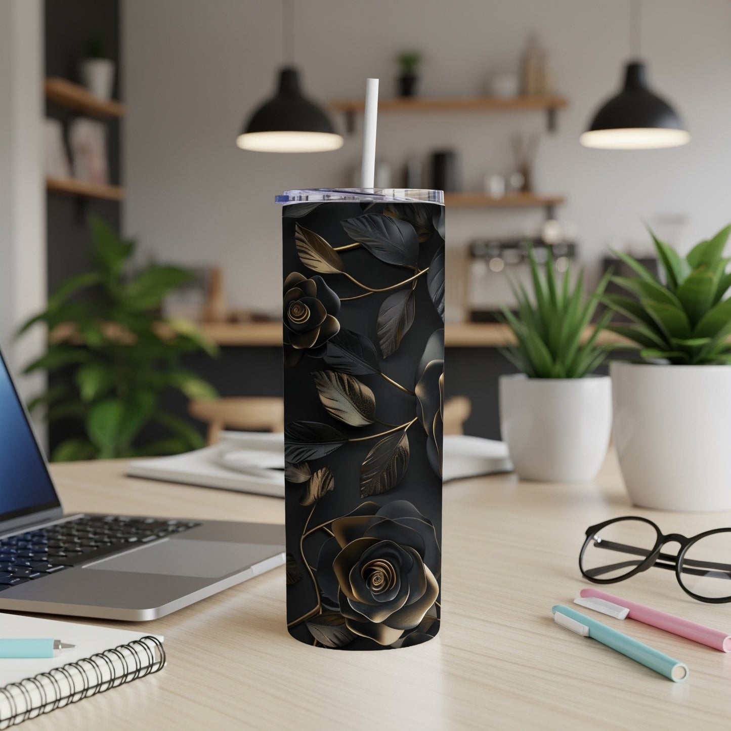 Black and gold floral tumbler with straw on a desk.