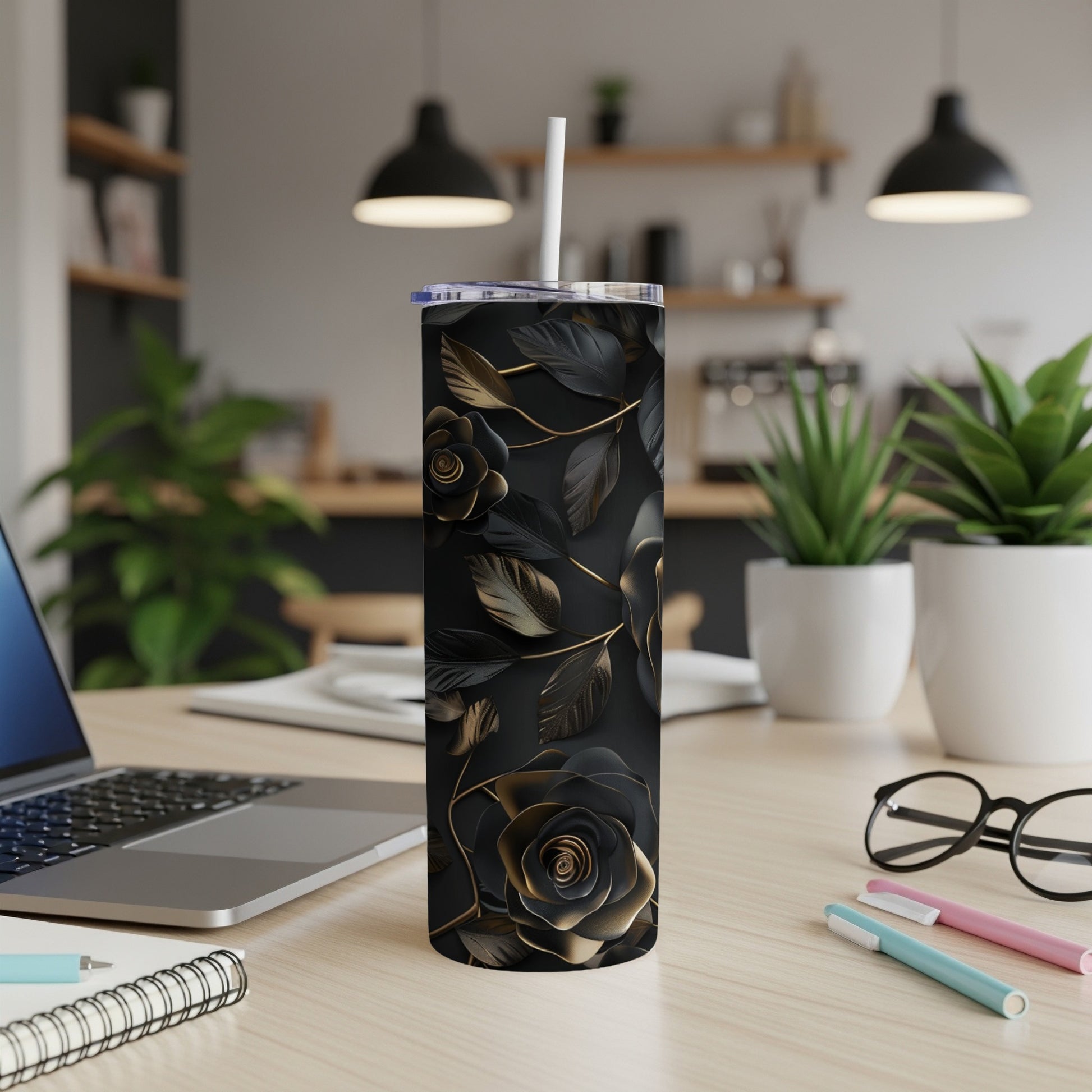 Black and gold floral tumbler with straw on a desk.