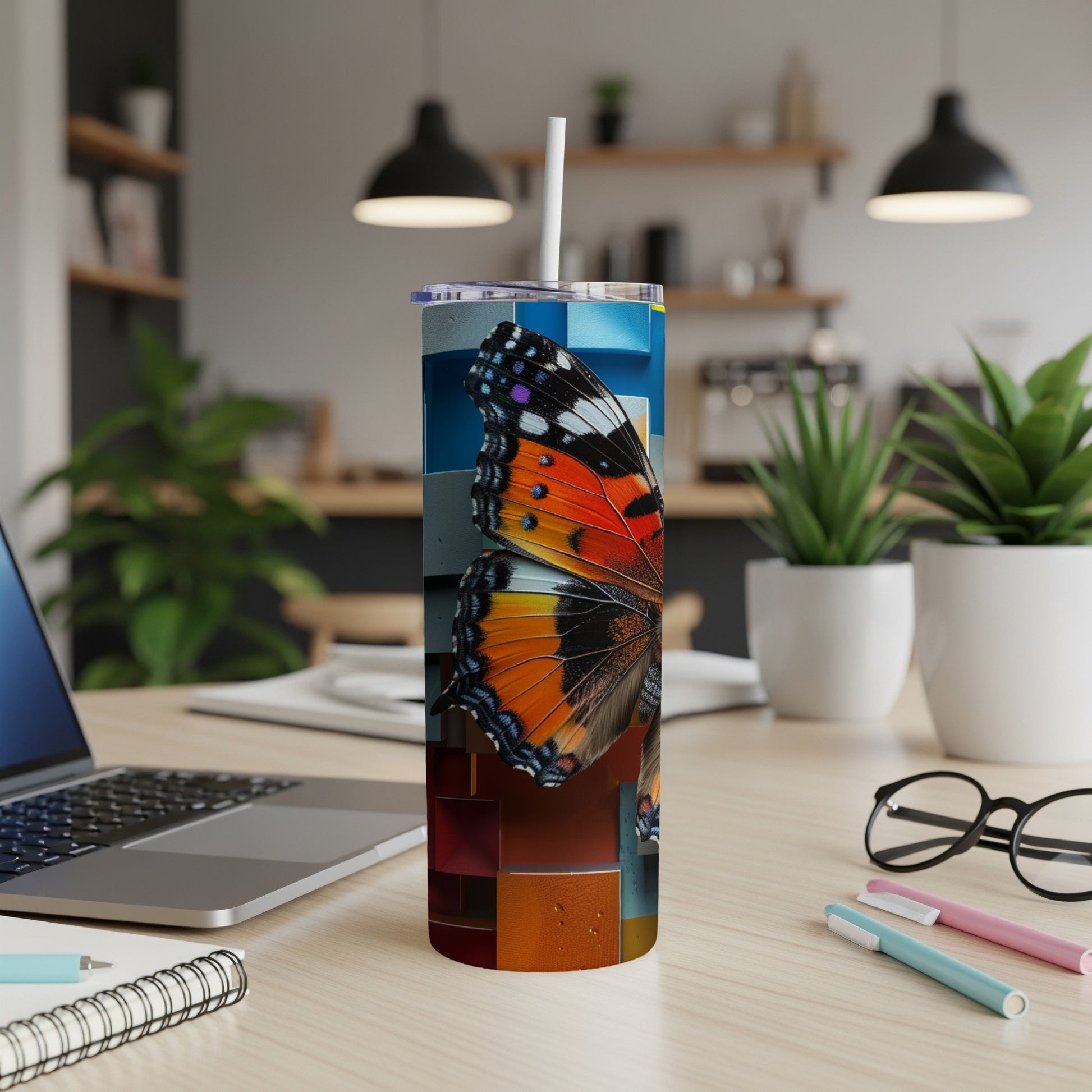 Tall tumbler with butterfly wing design on a desk.