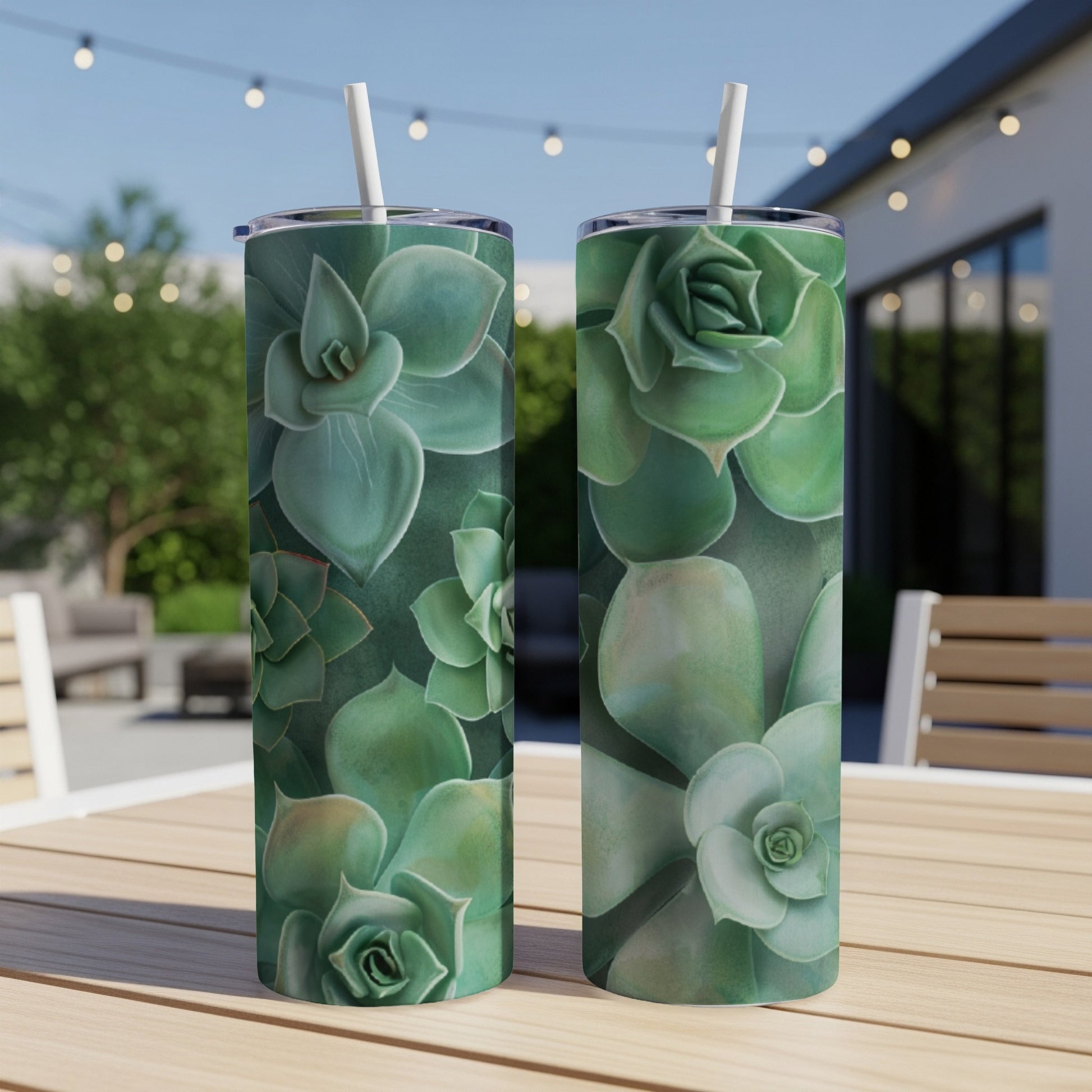 Two green succulent tumblers with straws on a wooden table outdoors.