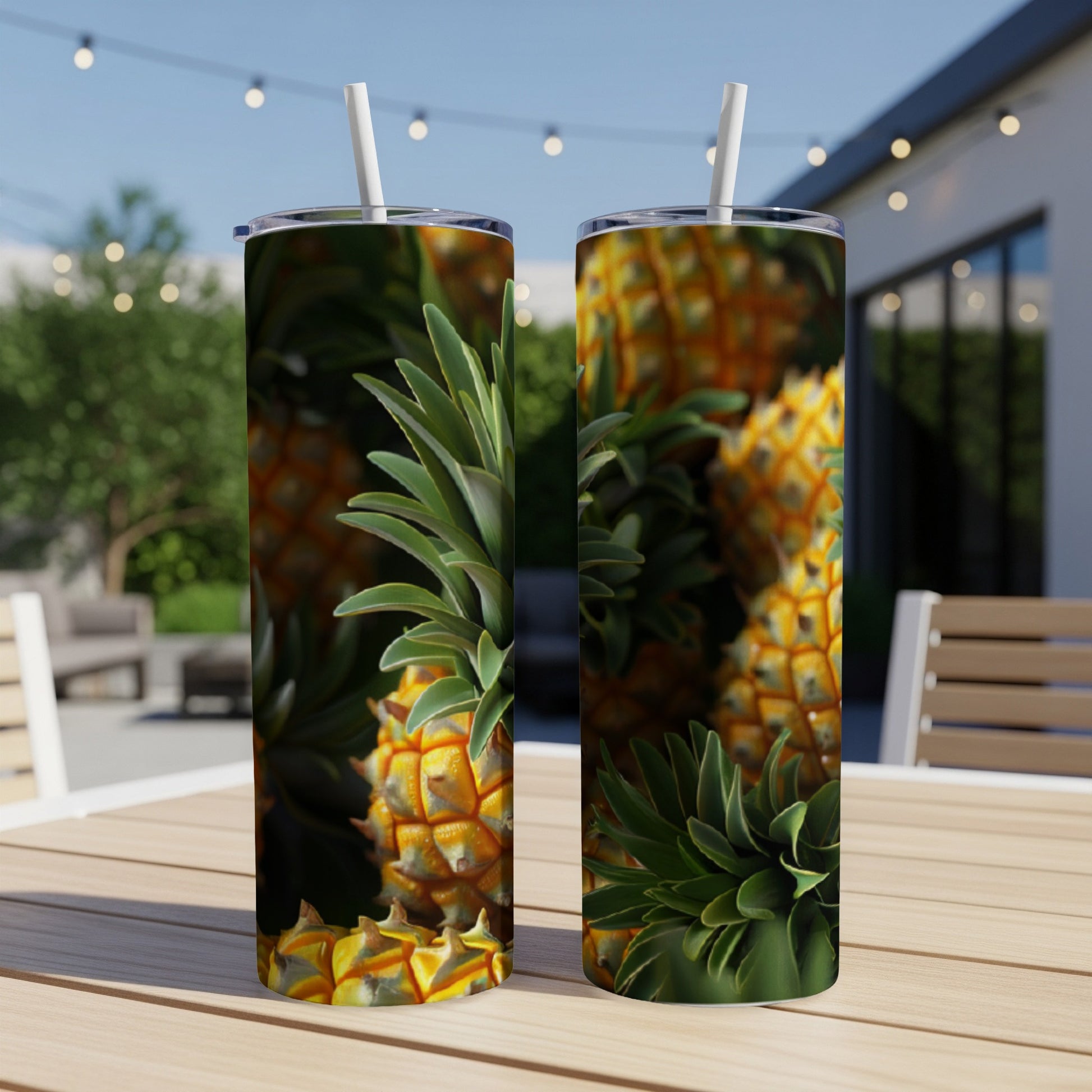 Two tumblers with a pineapple design, sitting on a wooden table outdoors.