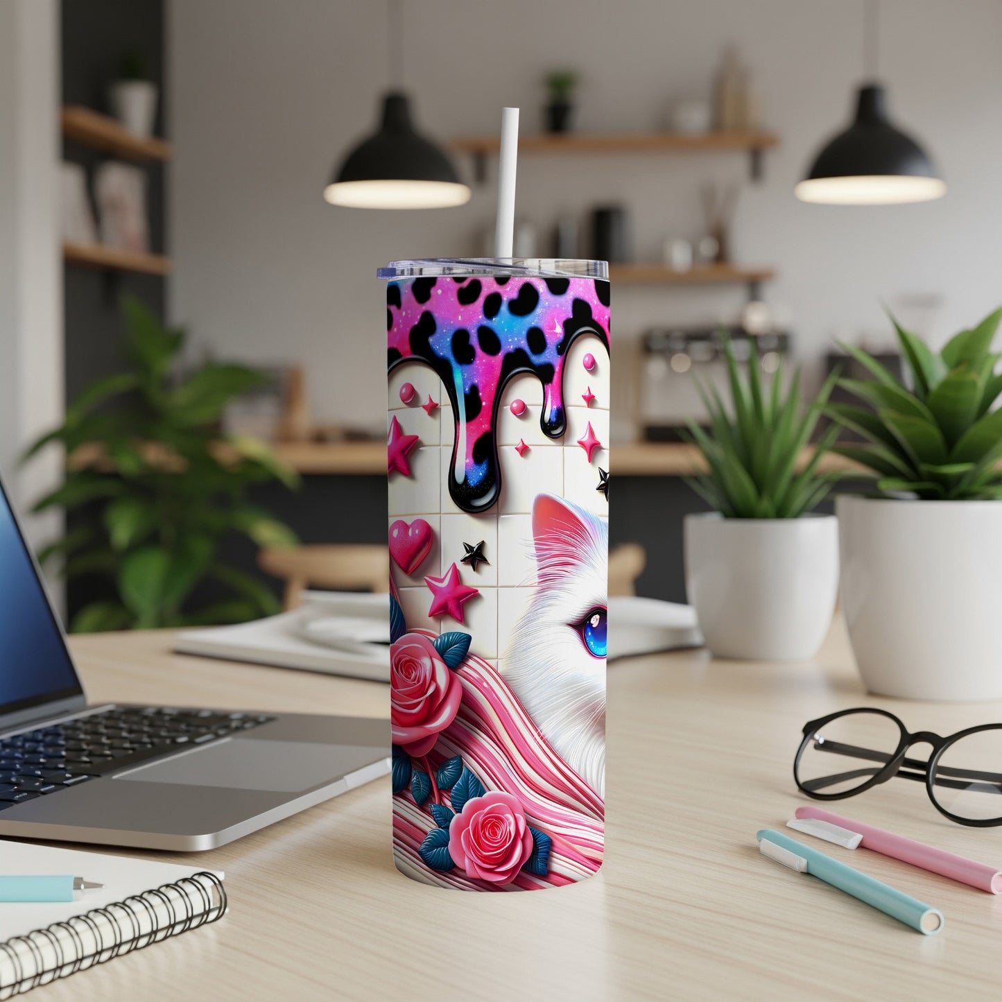 Pink and white cat tumbler with colorful drips and stars, on a desk.