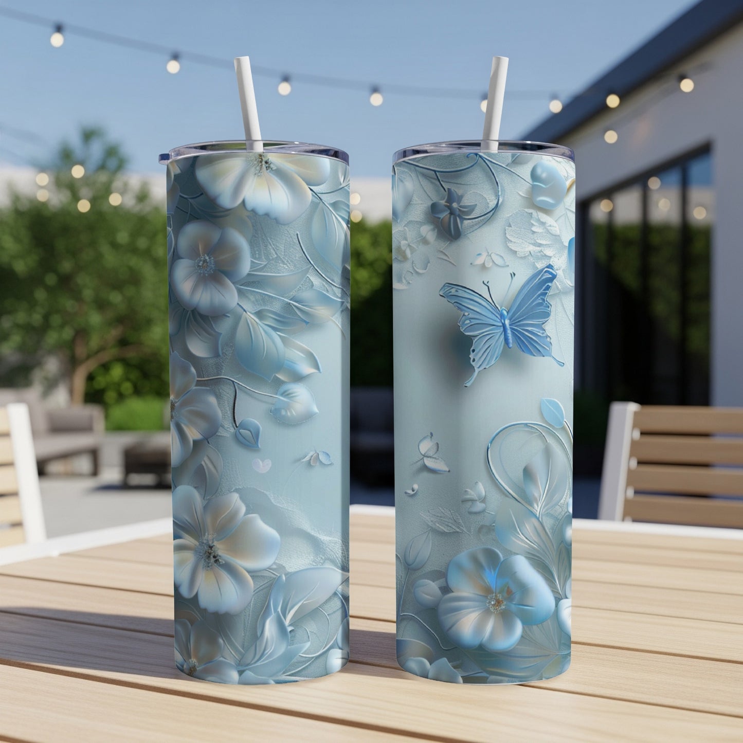 Two blue tumblers with floral and butterfly designs on a wooden table.