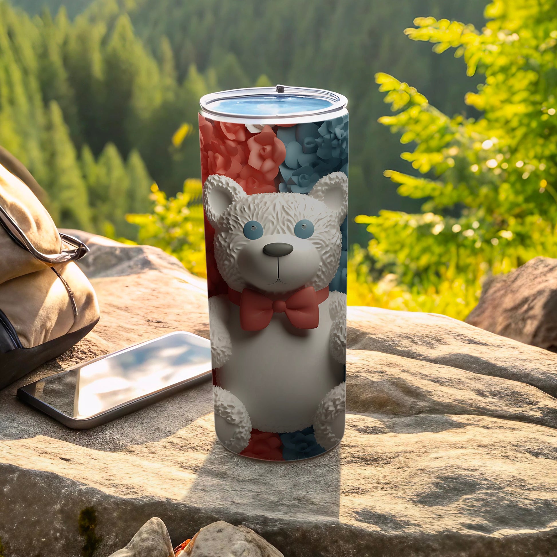 White teddy bear with bow on floral tumbler with phone and bag.