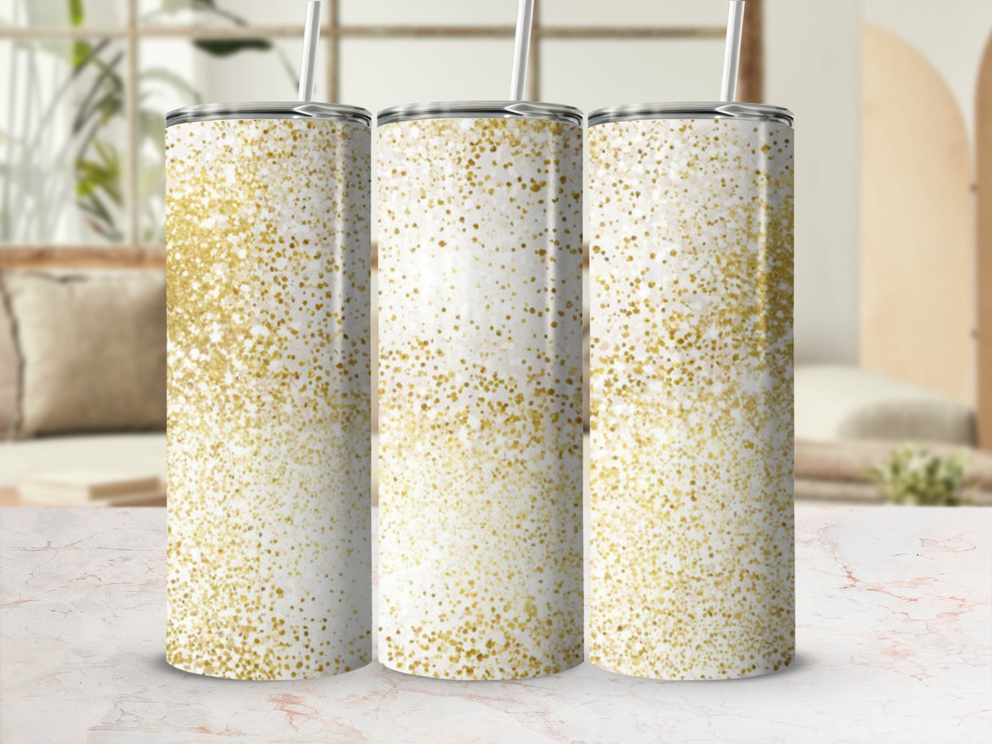 Three white tumblers with gold glitter accents and straws.