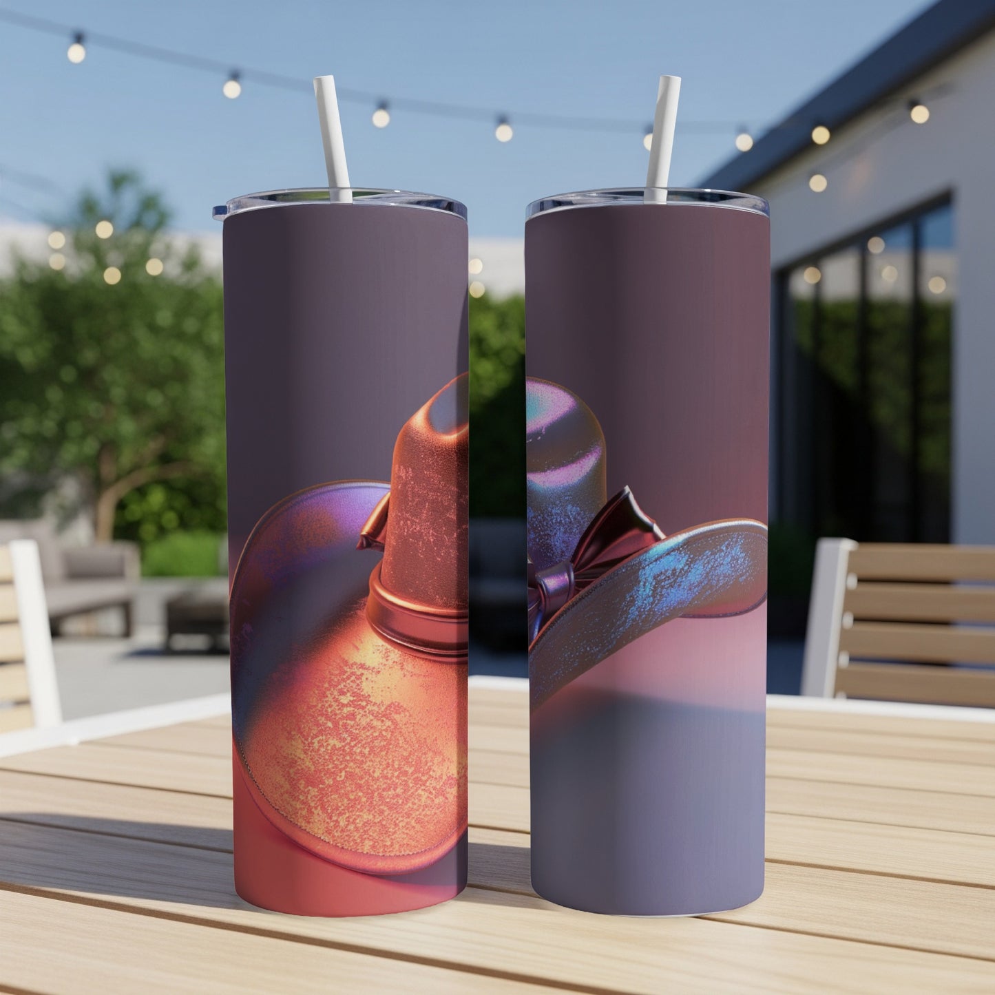 Two metallic cowboy hats on tumblers with straws on a wooden table.