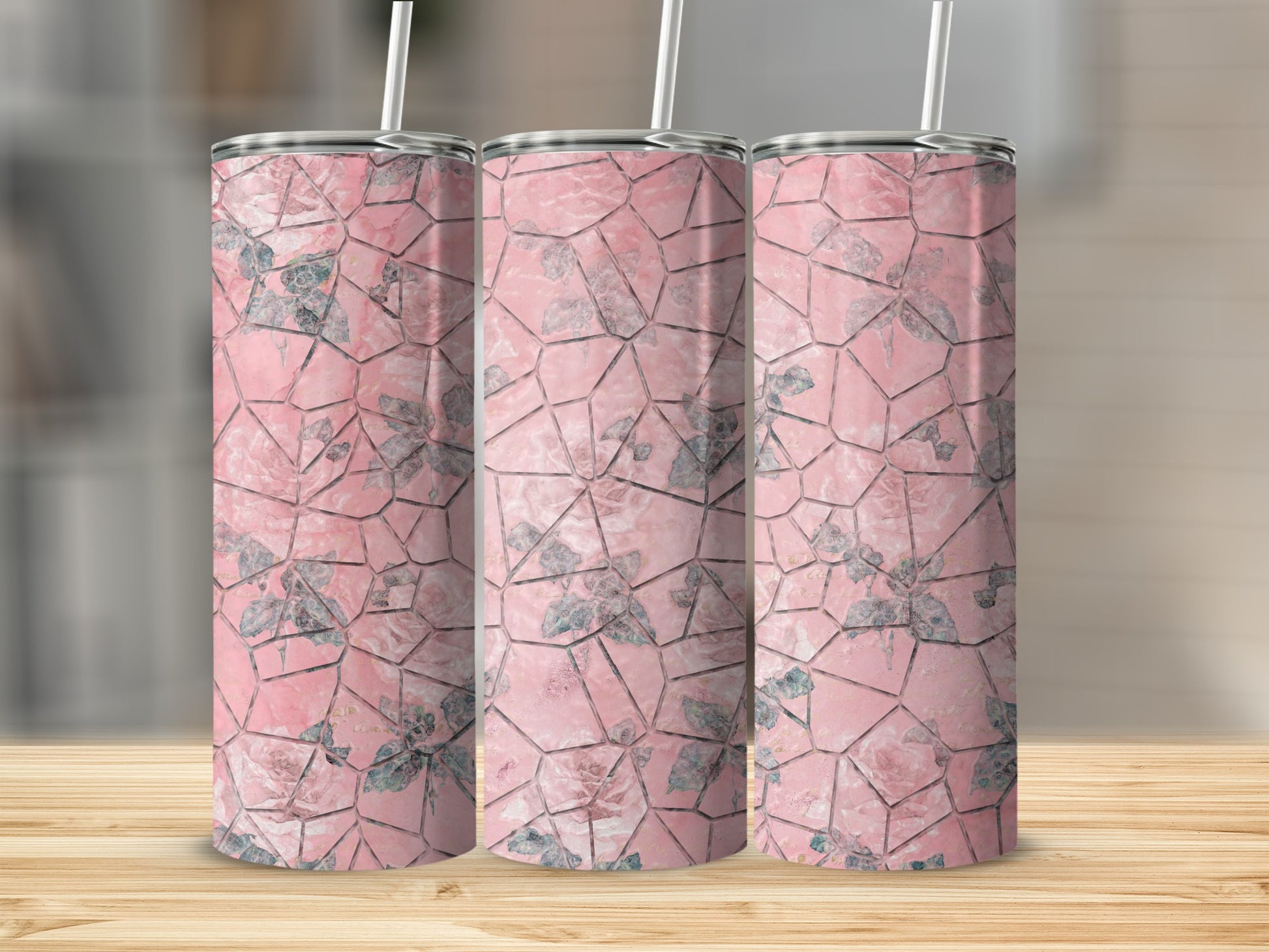 Three pink tumblers with a rose floral mosaic pattern, standing on a wooden surface.