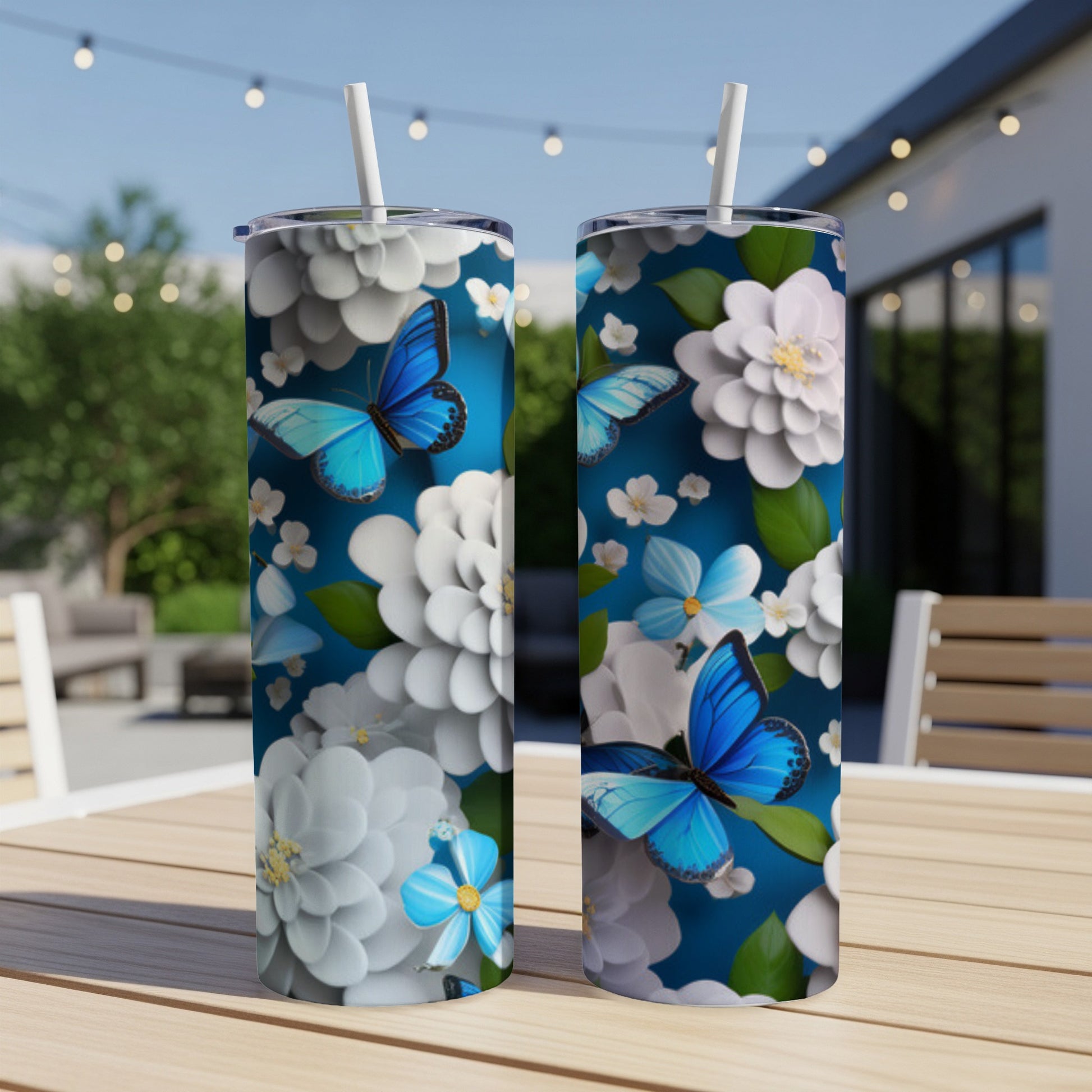 Blue butterflies and white flowers adorn two blue tumblers on a wooden table.