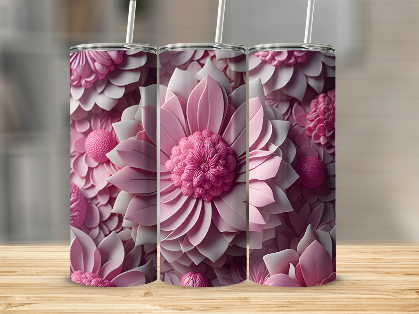 Three pink floral tumblers with straws on a wooden surface.