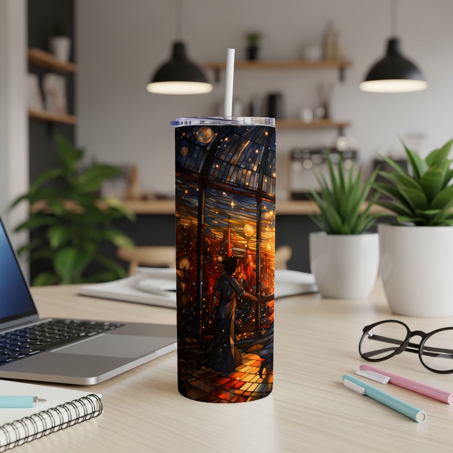 Stained glass tumbler with cityscape and stars, standing on a desk.