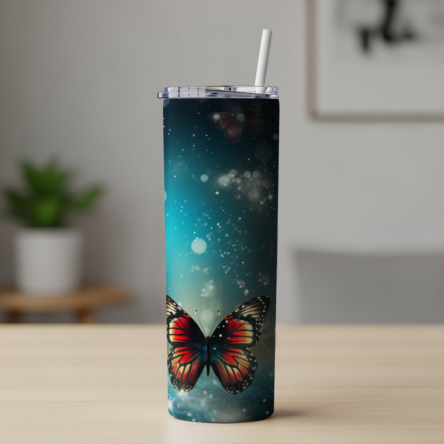 Tall tumbler with blue galaxy and butterfly design, featuring a straw.