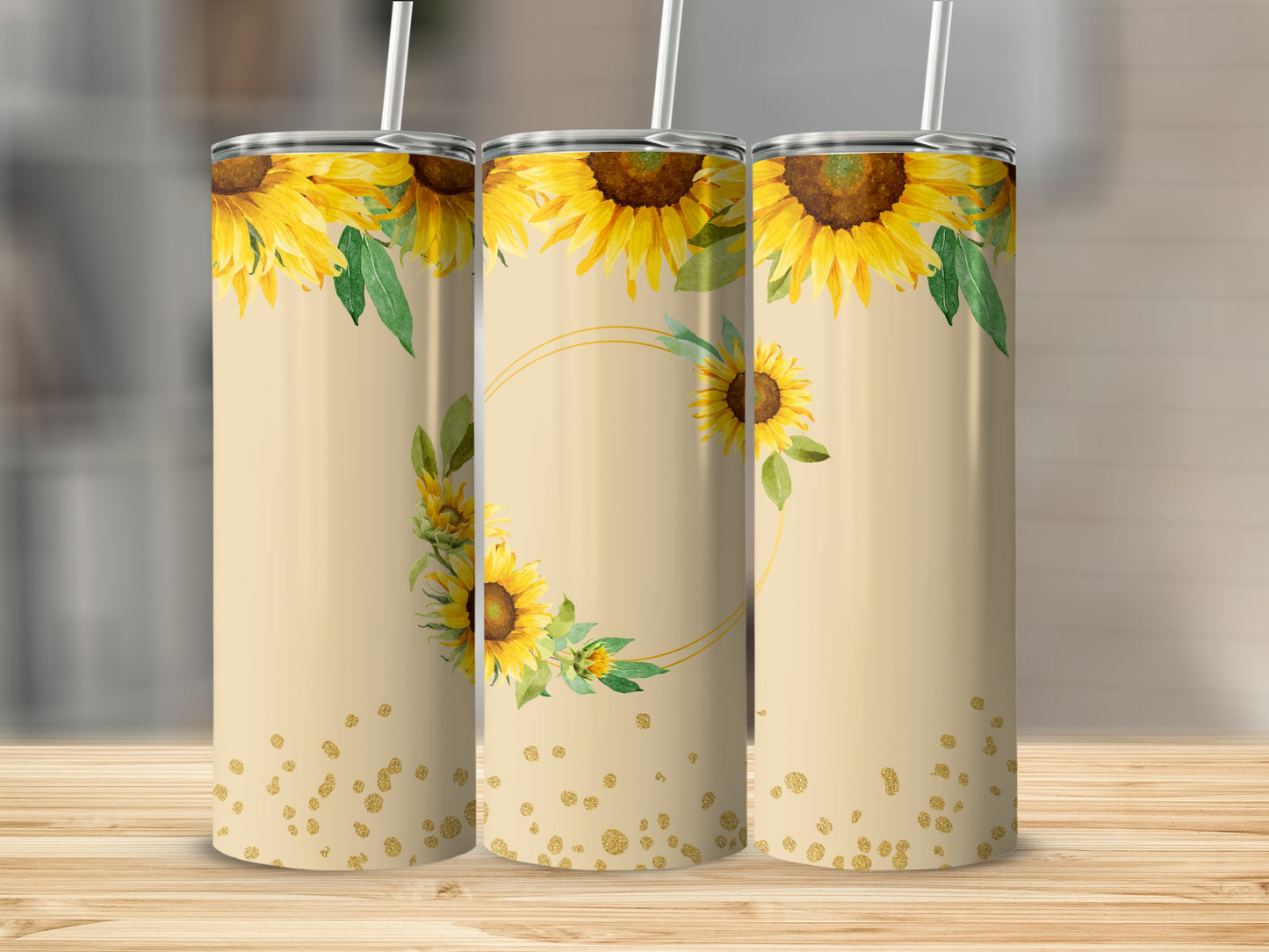 Three tall tumblers with sunflowers and gold glitter design on a wooden surface.