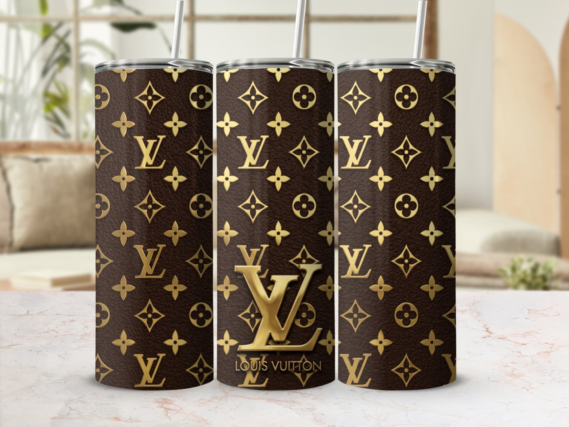 Three tumblers with brown and gold Louis Vuitton monogram pattern and straws.