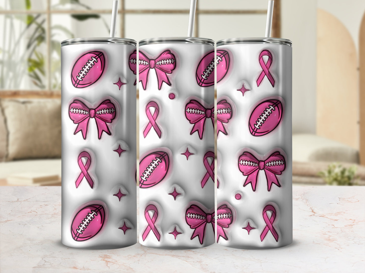 Pink footballs, bows, and ribbons on three white tumblers with straws.