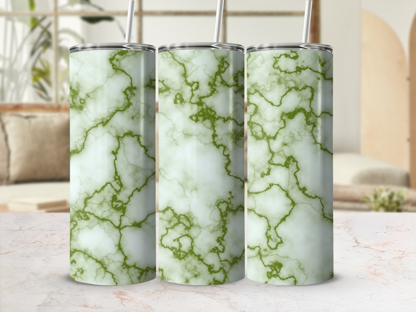 Three white and green marble pattern tumblers with straws on a marble surface.